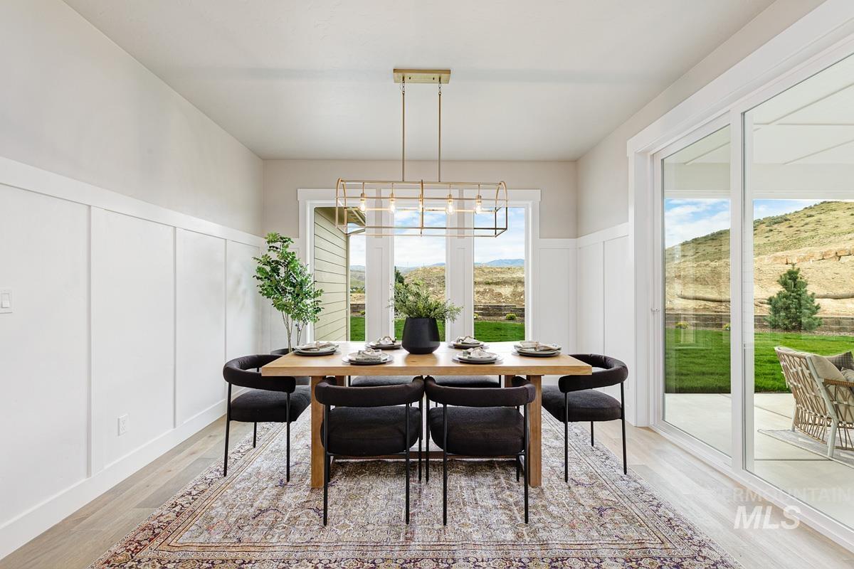 Dining room featuring a decorative wall, healthy amount of natural light, wainscoting, light wood finished floors, and a chandelier