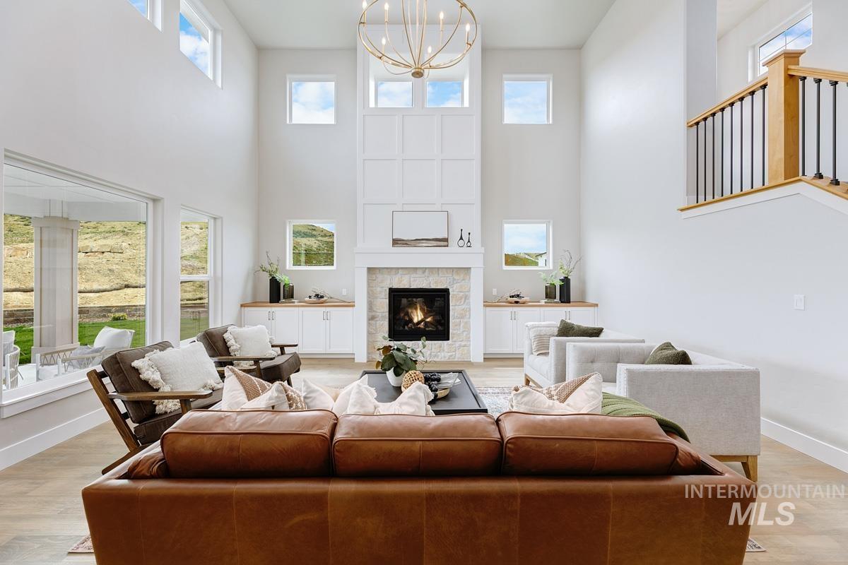 Living area featuring light wood-style floors, a high ceiling, a fireplace, and a chandelier