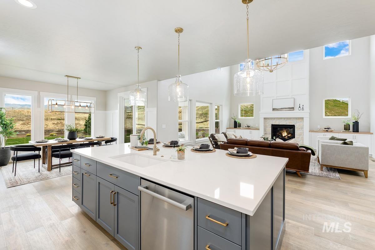Kitchen with a chandelier, hanging light fixtures, stainless steel dishwasher, a glass covered fireplace, and a towering ceiling