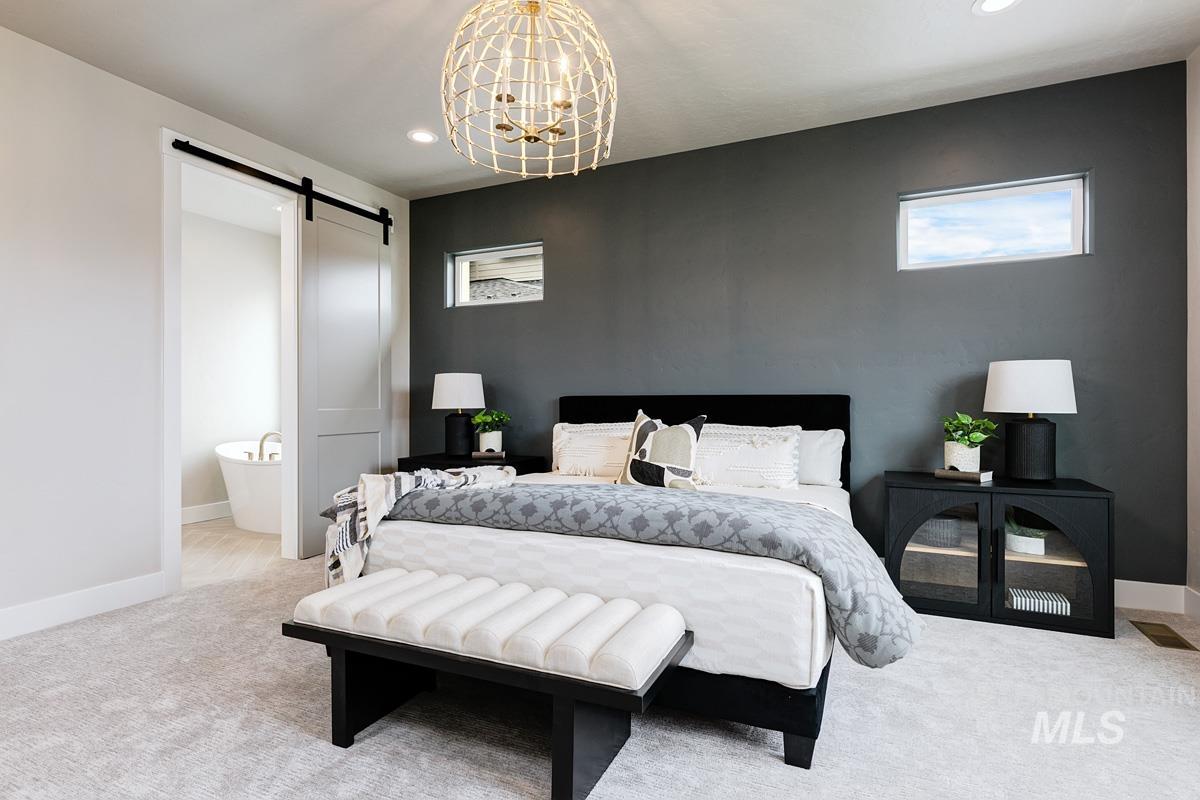 Bedroom with a barn door, a chandelier, recessed lighting, carpet, and ensuite bathroom