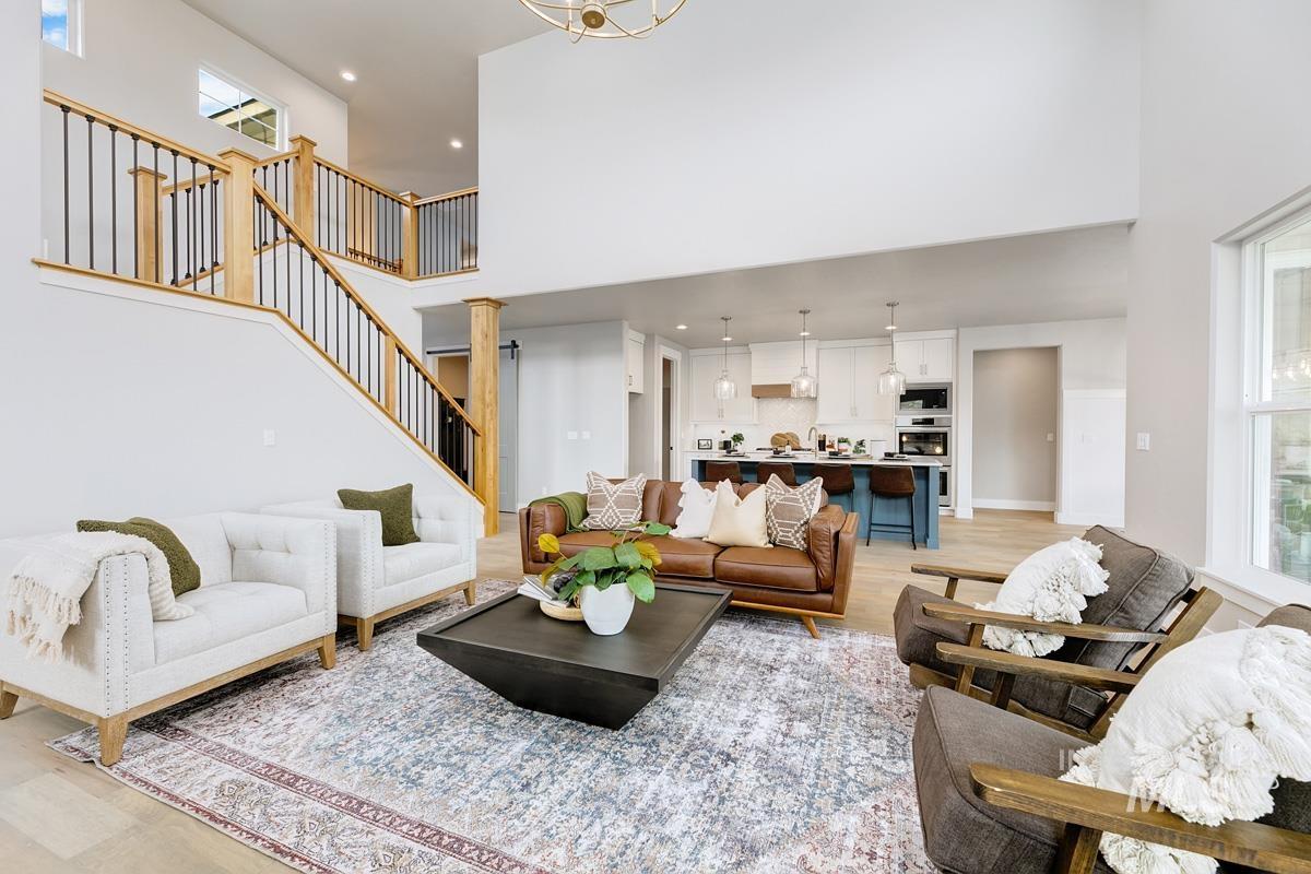 Living area with light wood finished floors, healthy amount of natural light, a high ceiling, recessed lighting, and stairs