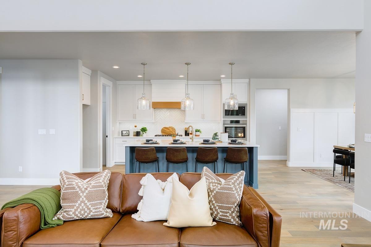 Kitchen with white cabinetry, a kitchen island with sink, a breakfast bar area, tasteful backsplash, and light wood-style flooring