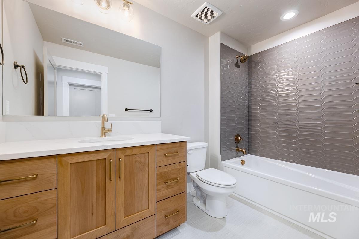 Full bath with bathing tub / shower combination, vanity, and light tile patterned floors