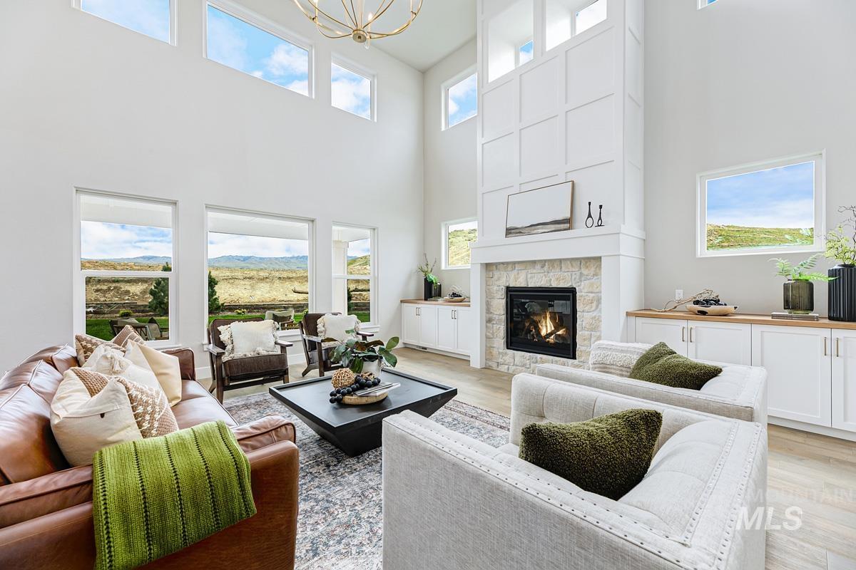 Living room featuring light wood finished floors, a fireplace, a towering ceiling, and a chandelier