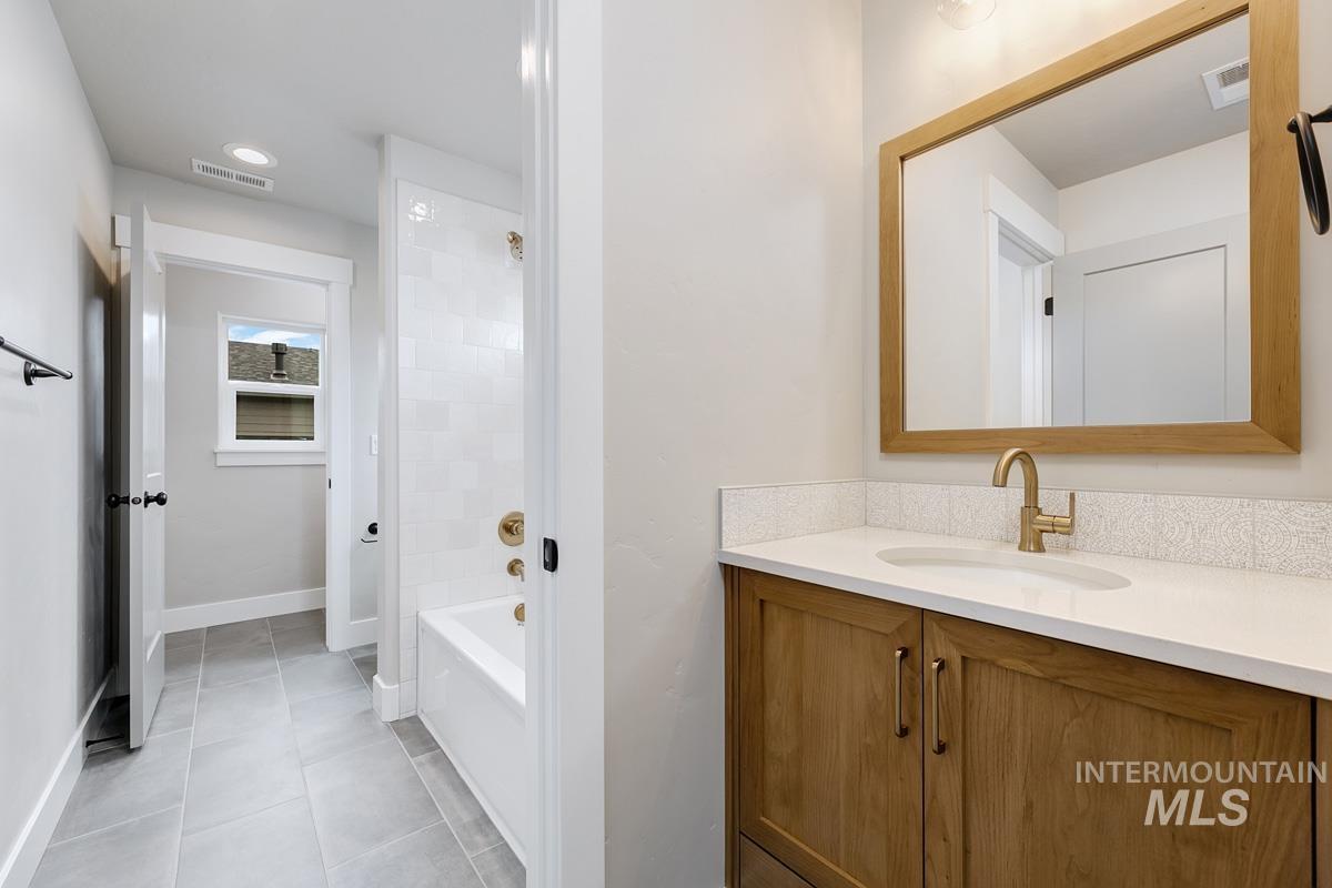 Bathroom featuring vanity, shower / tub combination, and light tile patterned floors