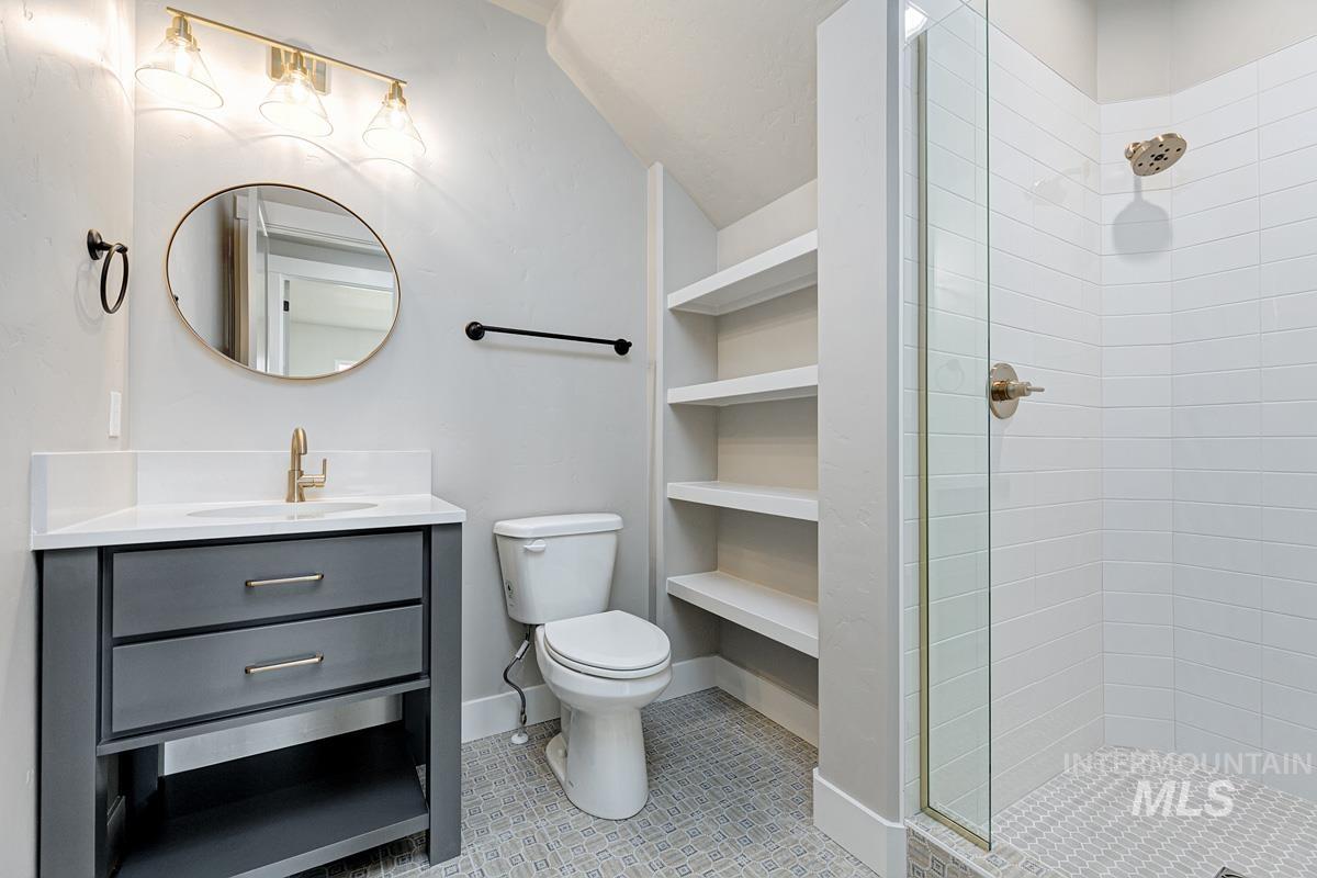 Bathroom featuring a tile shower, vanity, light tile patterned flooring, and built in shelves