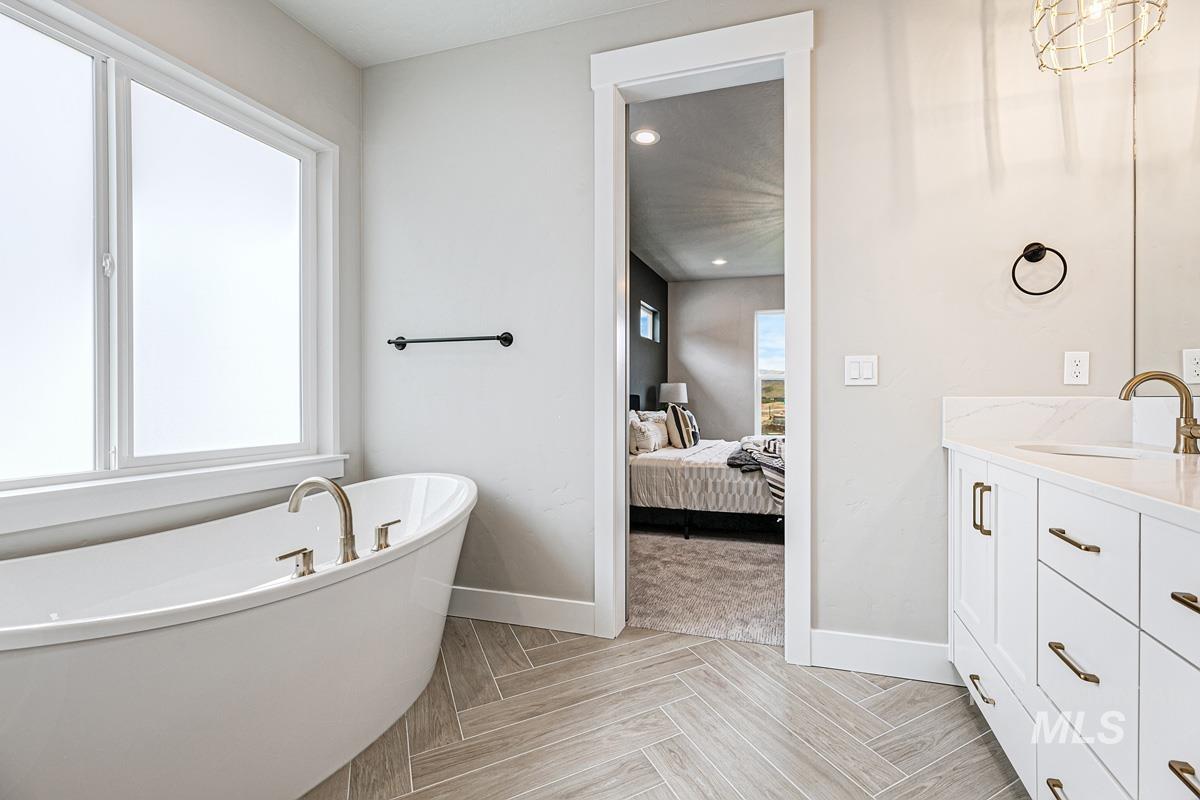 Ensuite bathroom with vanity, a freestanding tub, and recessed lighting