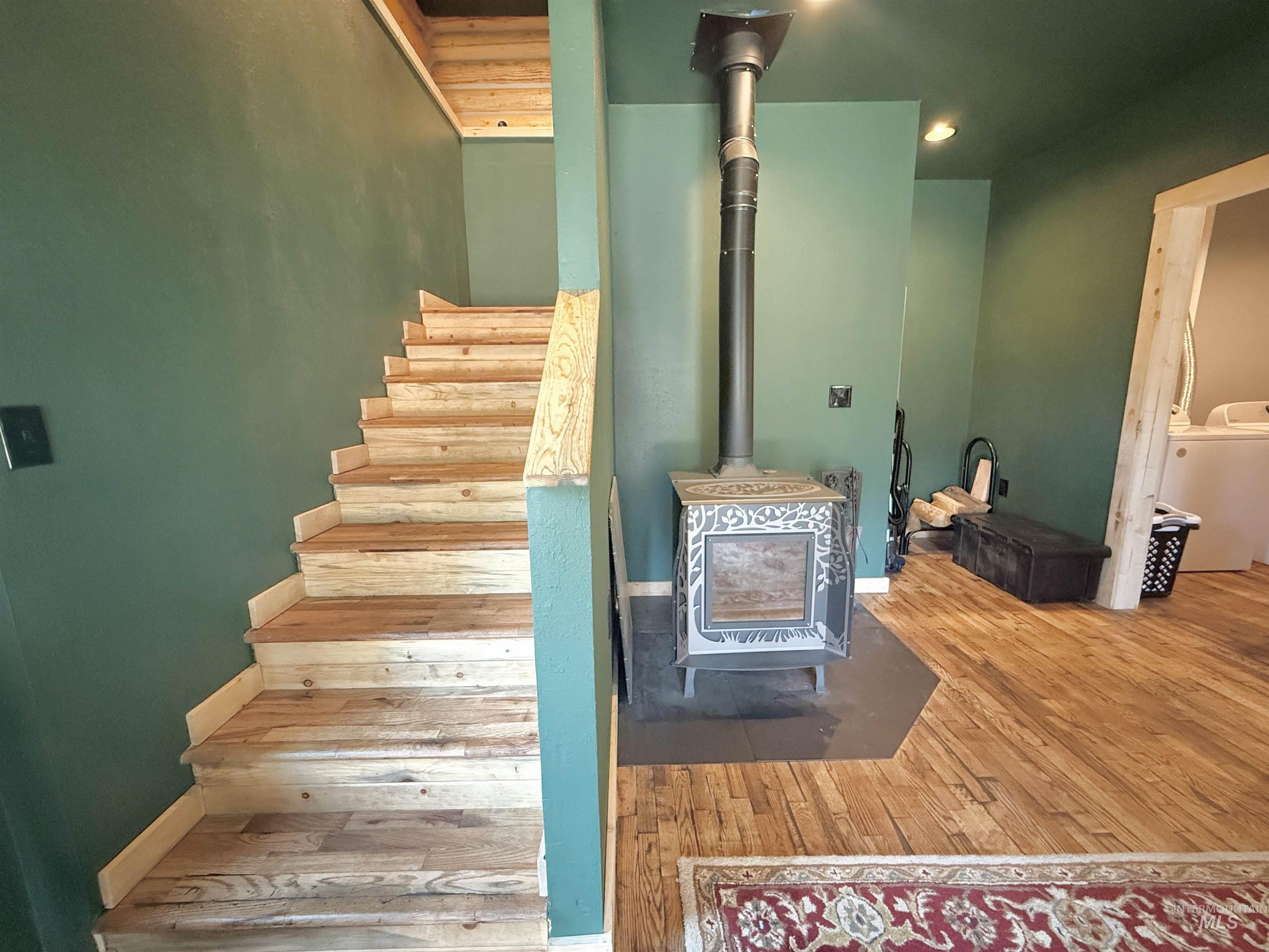 Staircase with wood-type flooring, a wood stove, and washer / dryer