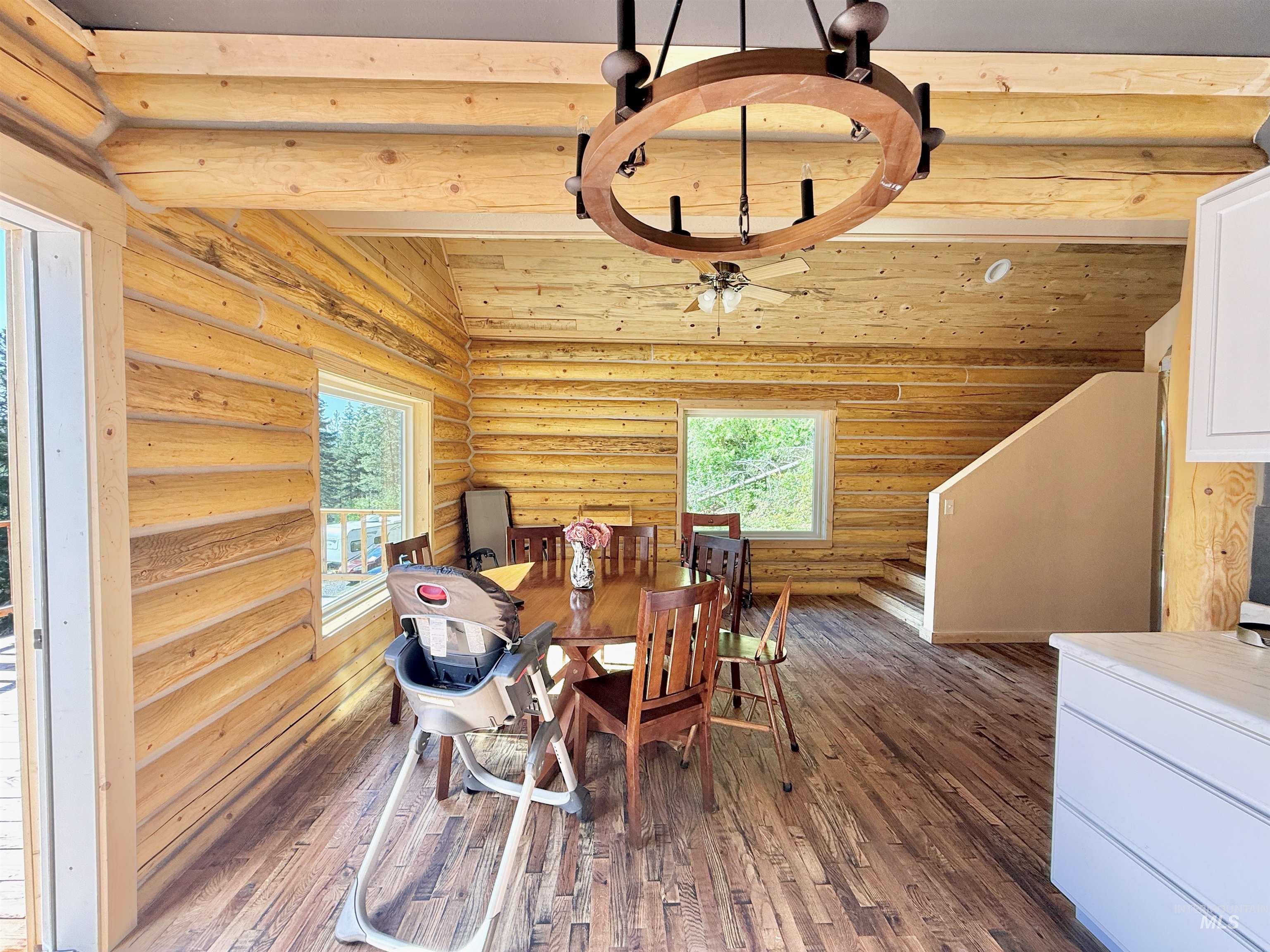Dining area with rustic walls, dark wood-style floors, and vaulted ceiling