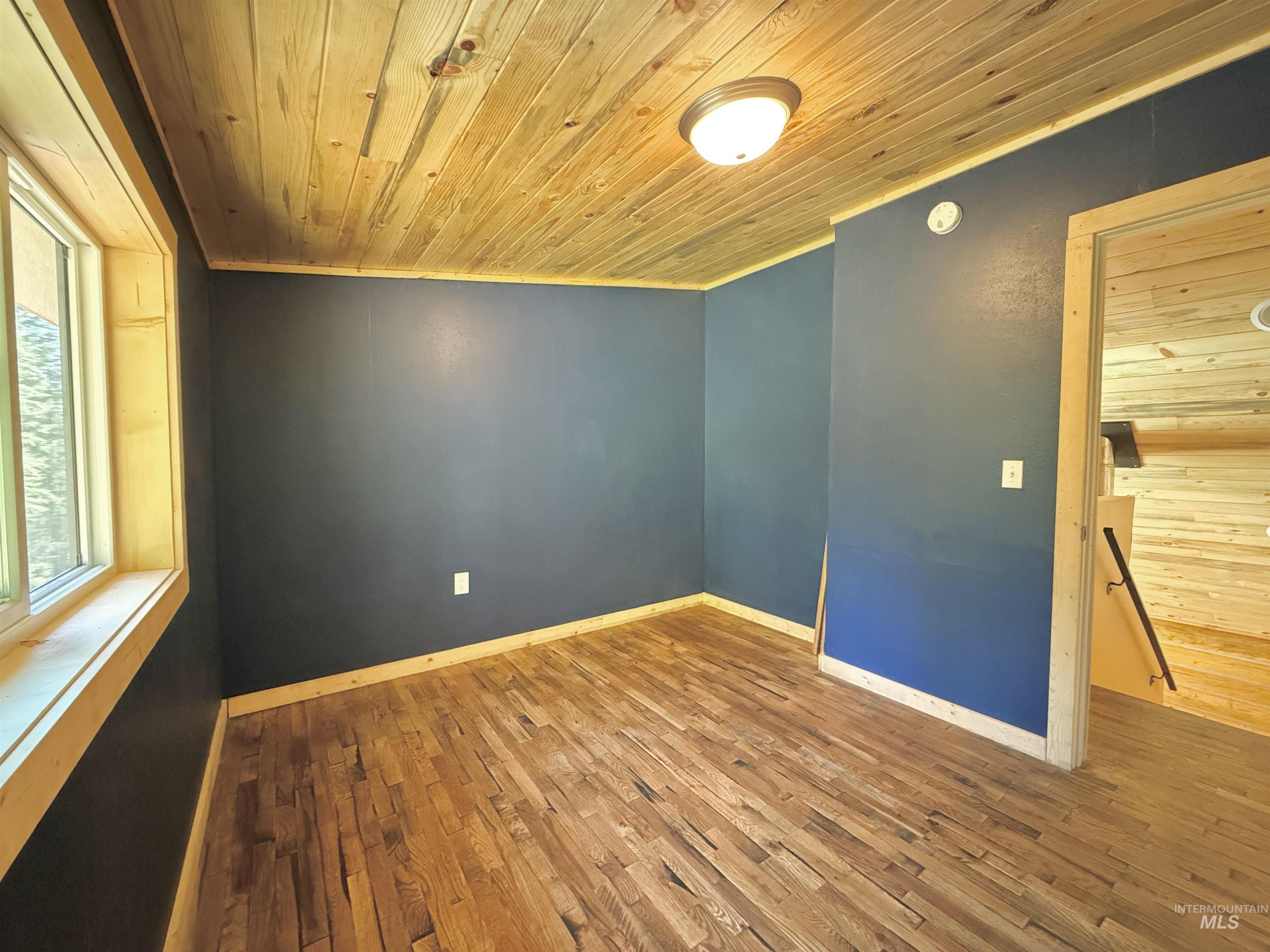 Spare room with wooden ceiling, wood finished floors, and crown molding