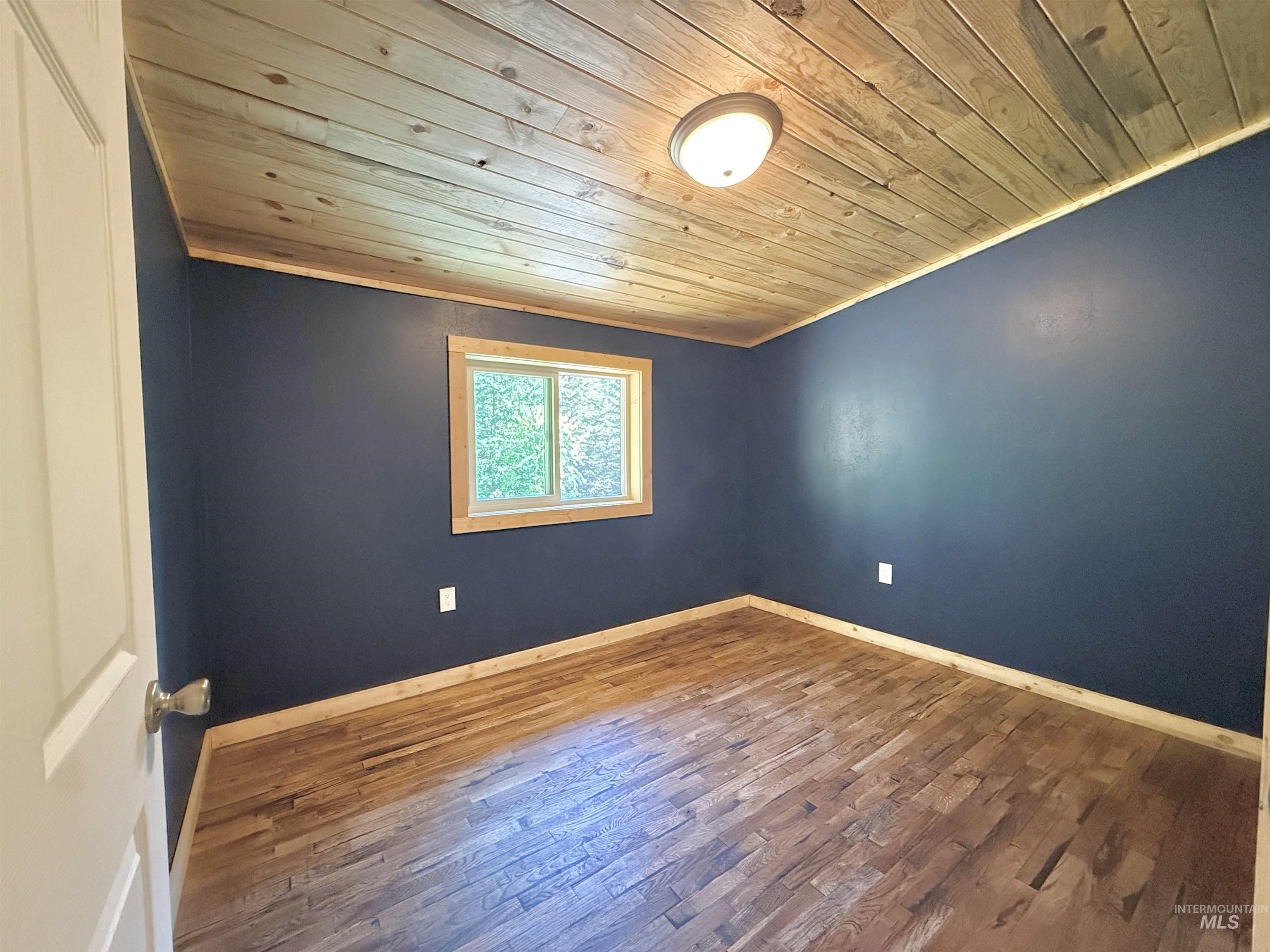 Empty room with wood ceiling, wood finished floors, and ornamental molding