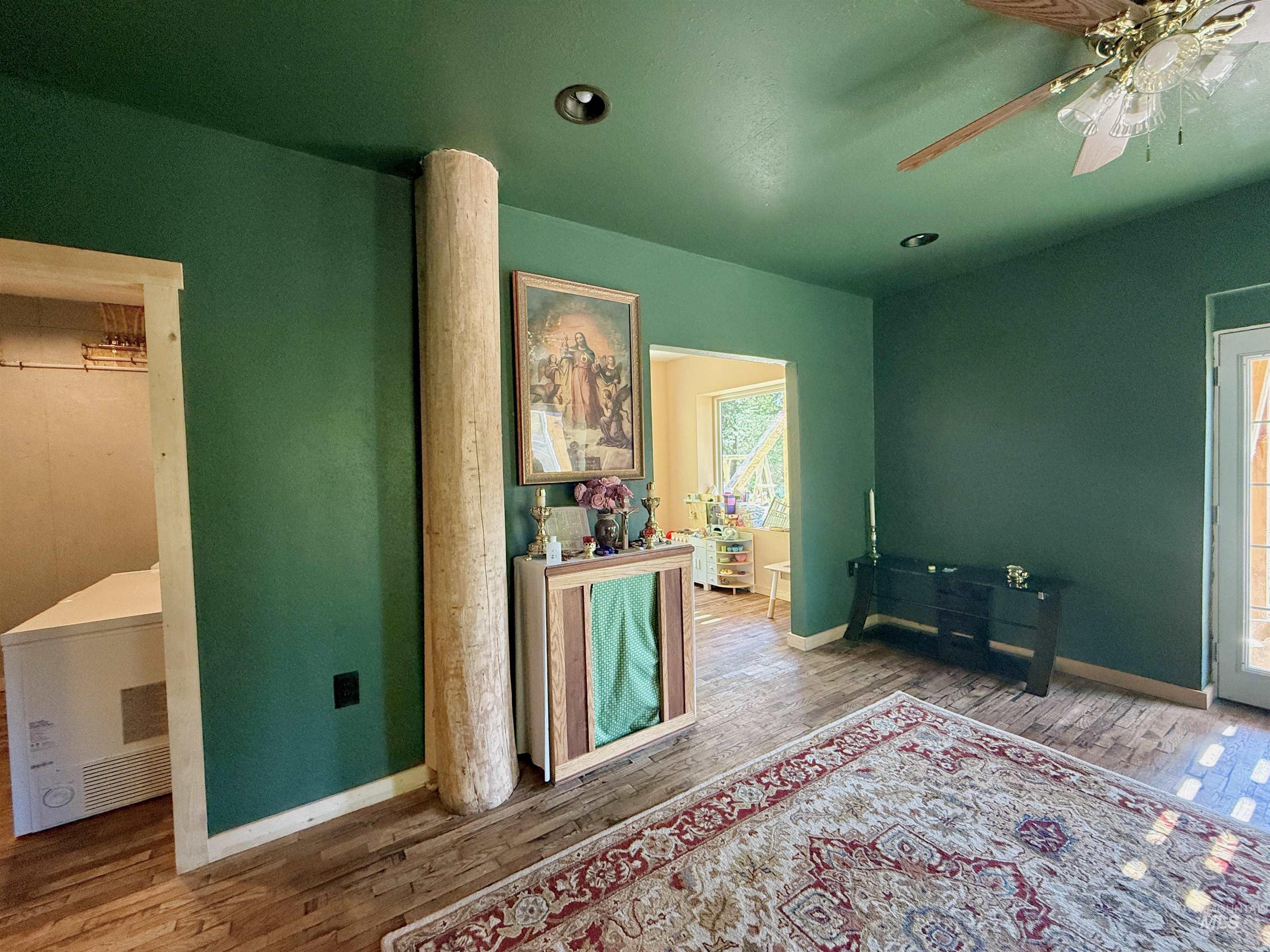 Bedroom featuring wood finished floors, a ceiling fan, and heating unit