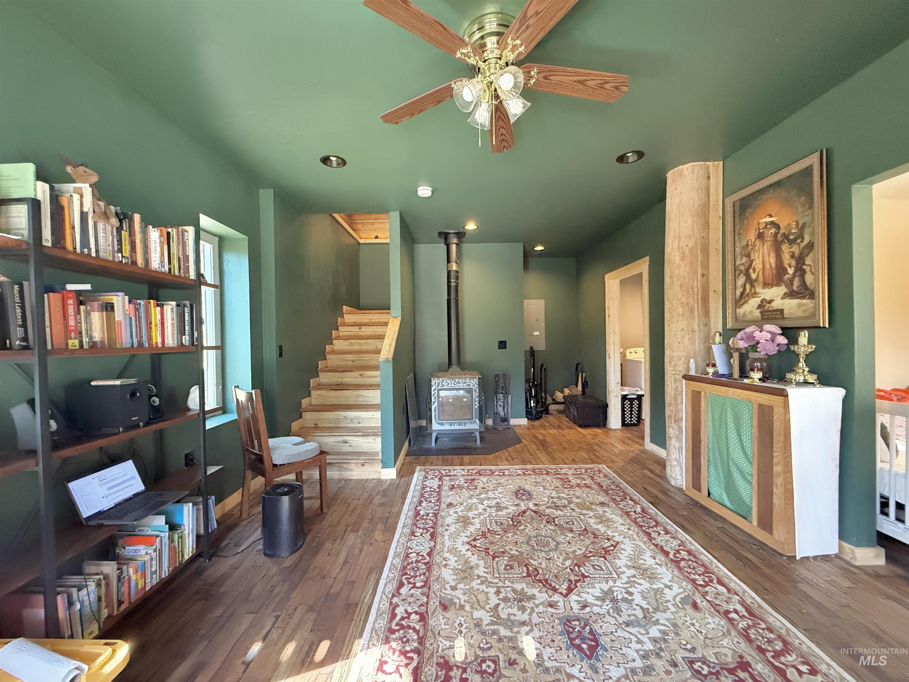 Living room with a wood stove, wood finished floors, ceiling fan, and recessed lighting