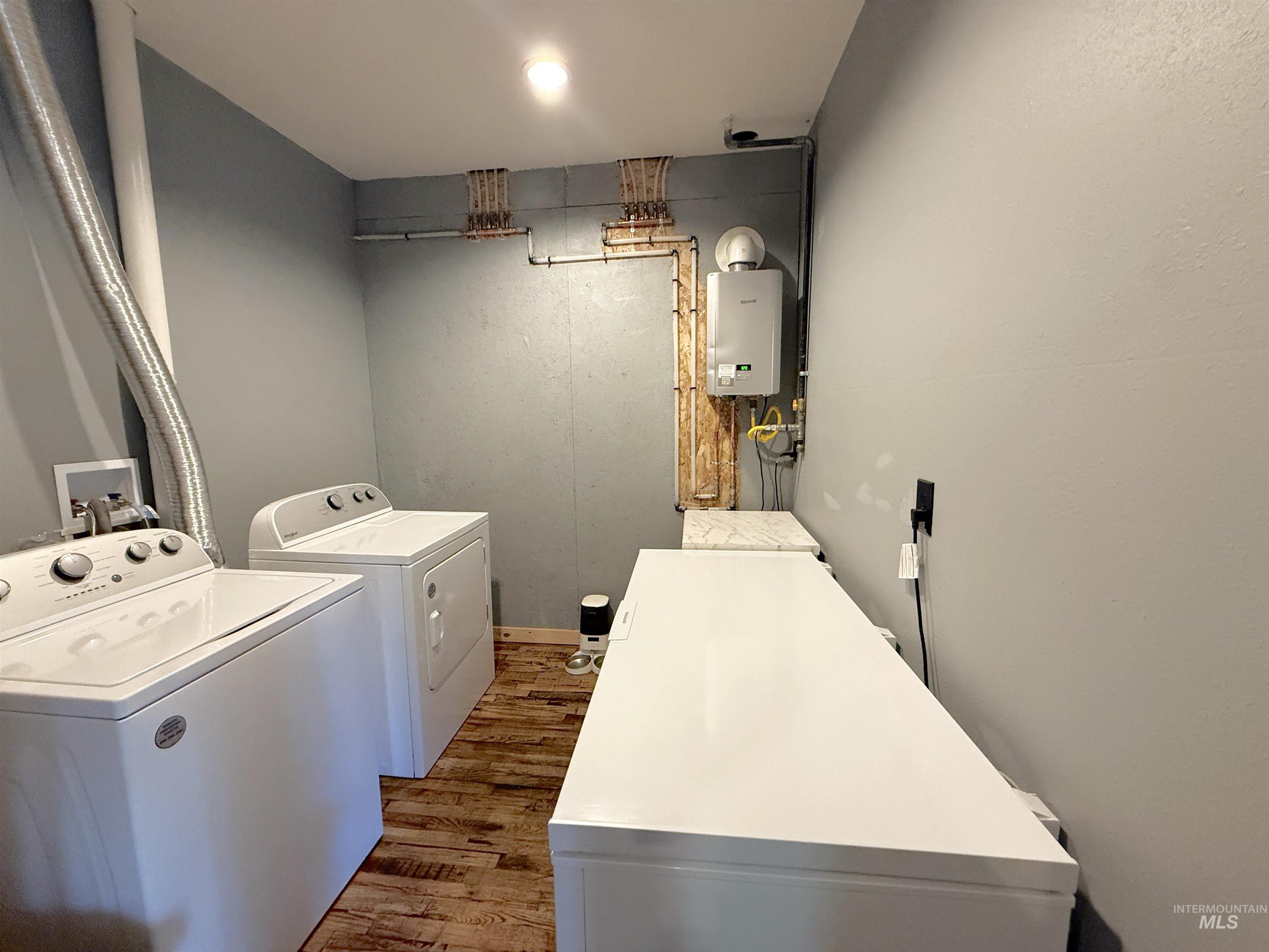 Laundry area featuring independent washer and dryer, dark wood-style flooring, and tankless water heater