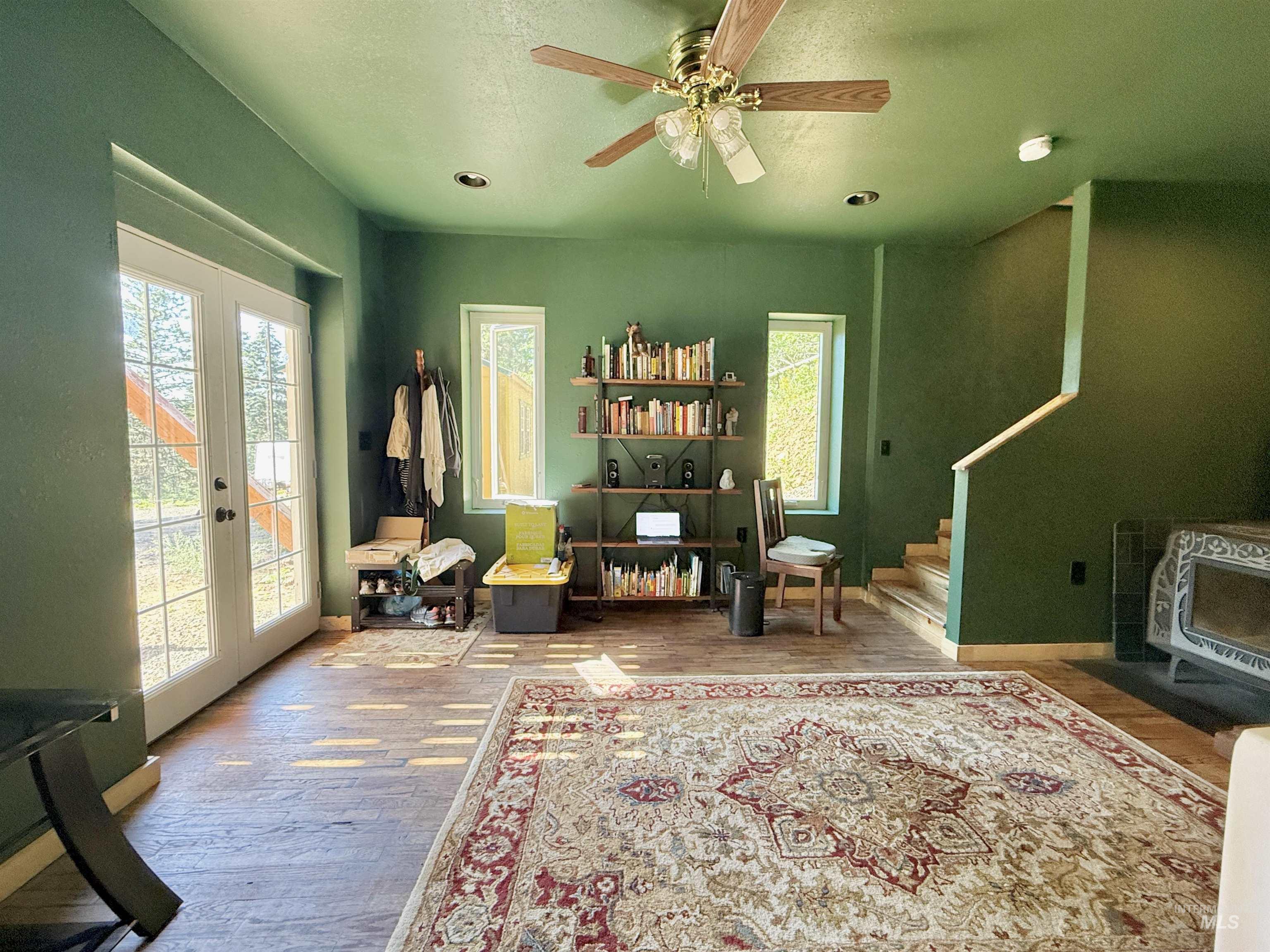 Living area featuring wood finished floors, french doors, stairway, and ceiling fan