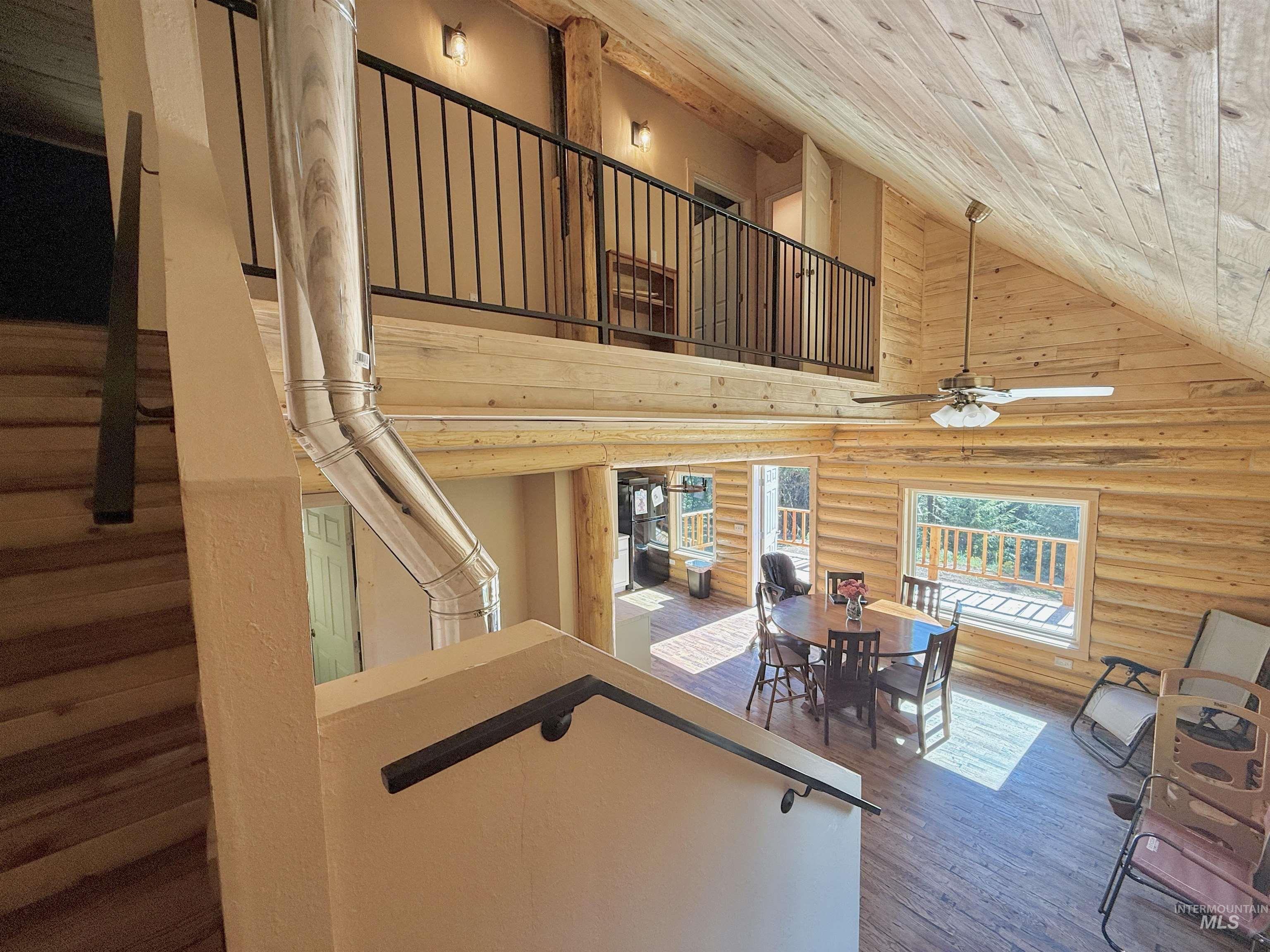 Stairs with wooden ceiling, ceiling fan, high vaulted ceiling, wood finished floors, and log walls