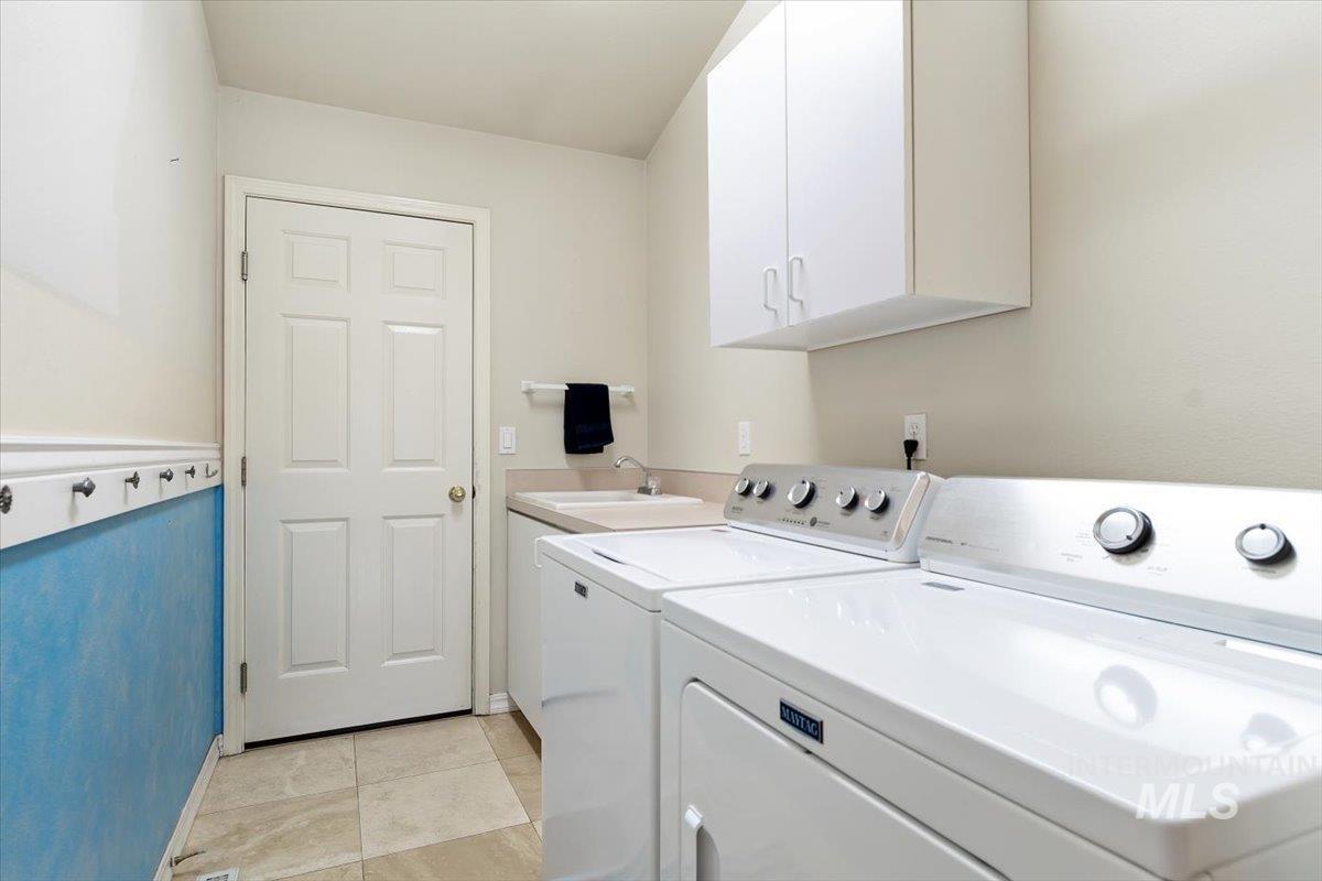 Laundry room with washer and clothes dryer, cabinet space, and light tile patterned floors