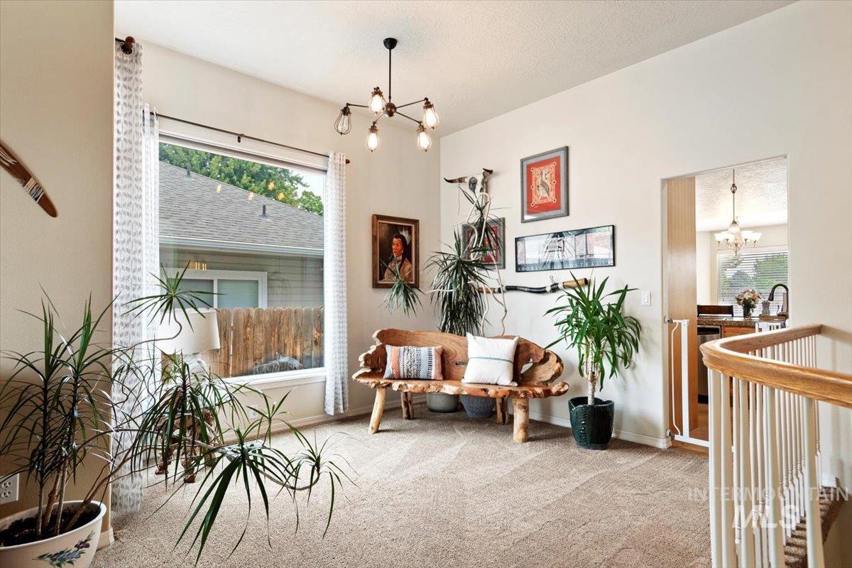 Living area featuring suspended lighting and light carpet