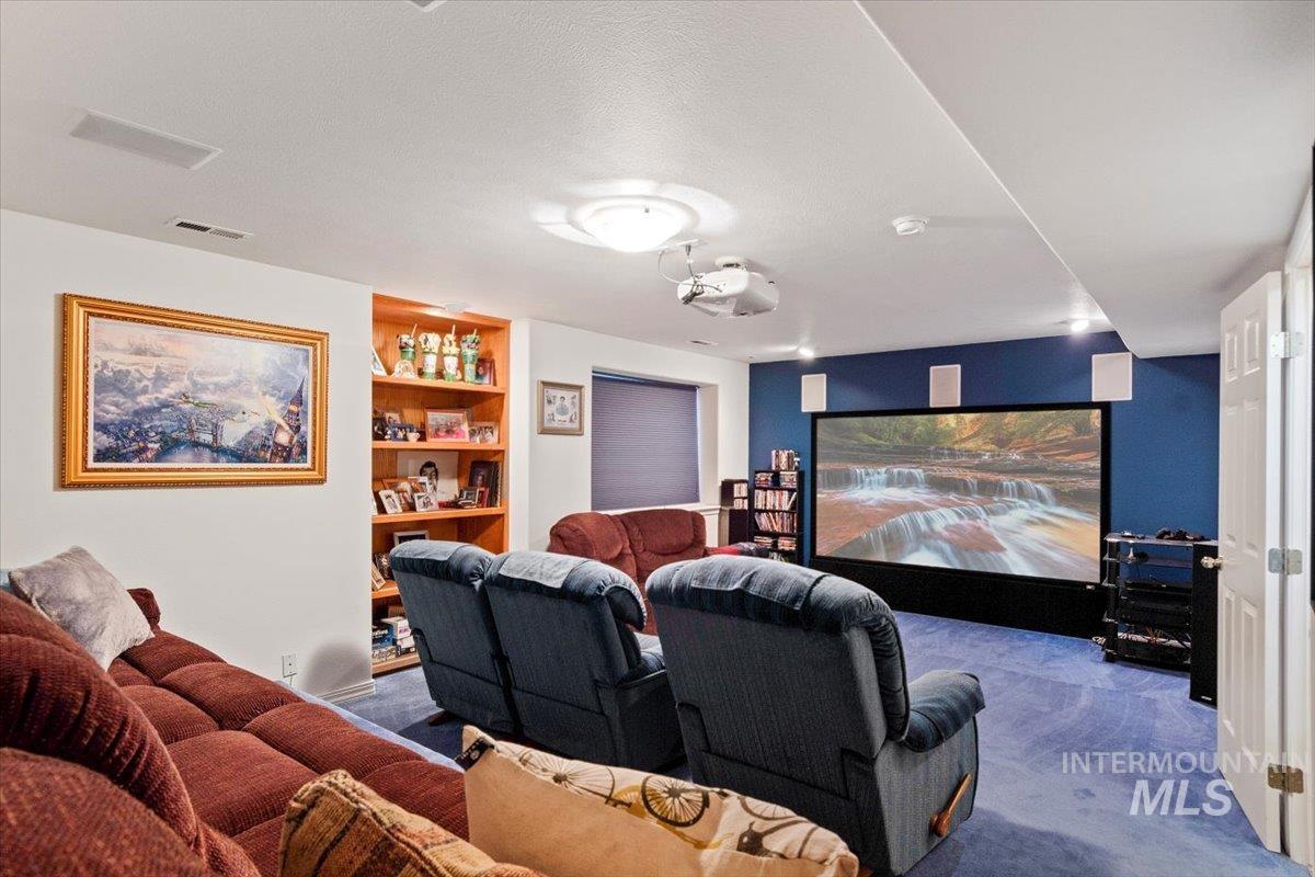 Carpeted cinema room featuring built in shelves and a textured ceiling