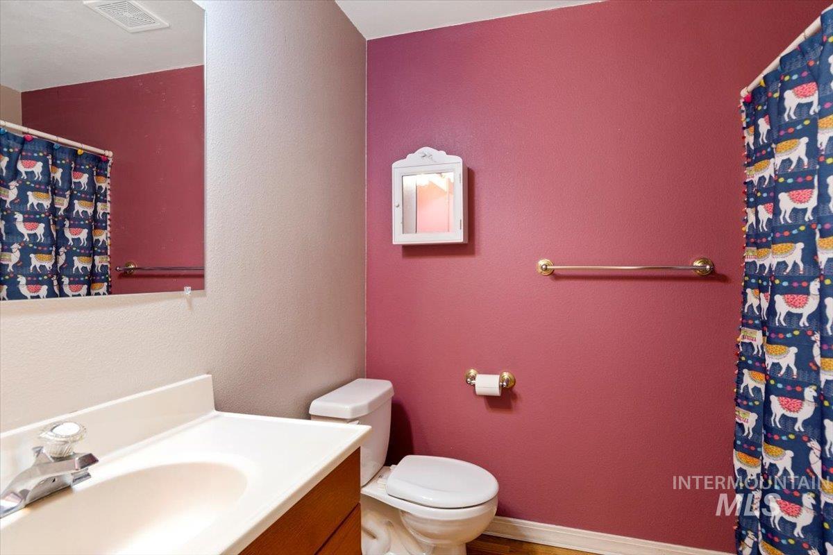 Bathroom with a textured wall, a shower with curtain, and vanity