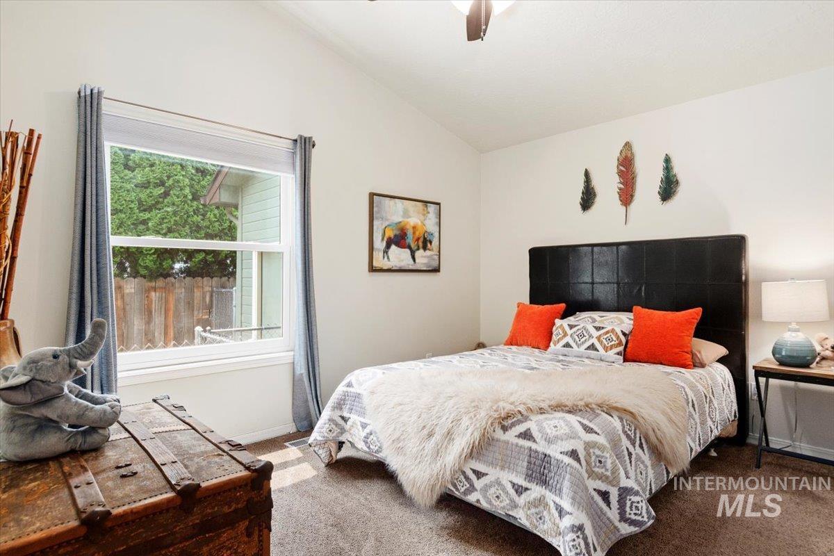 Carpeted bedroom featuring lofted ceiling and a ceiling fan