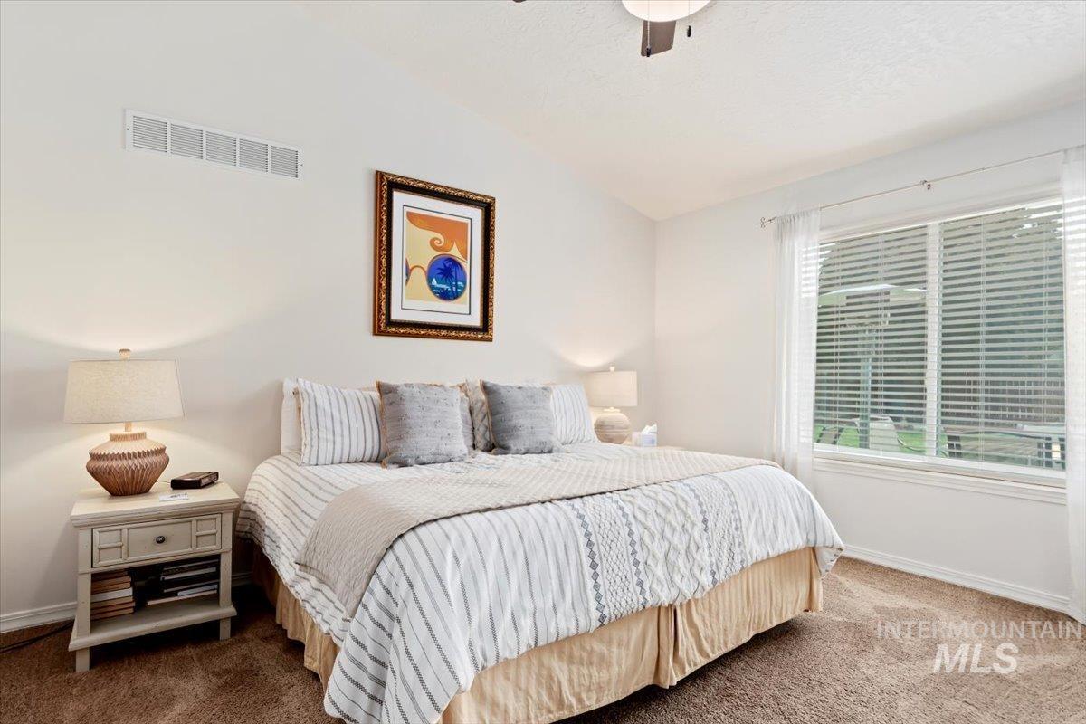 Carpeted bedroom featuring lofted ceiling and ceiling fan