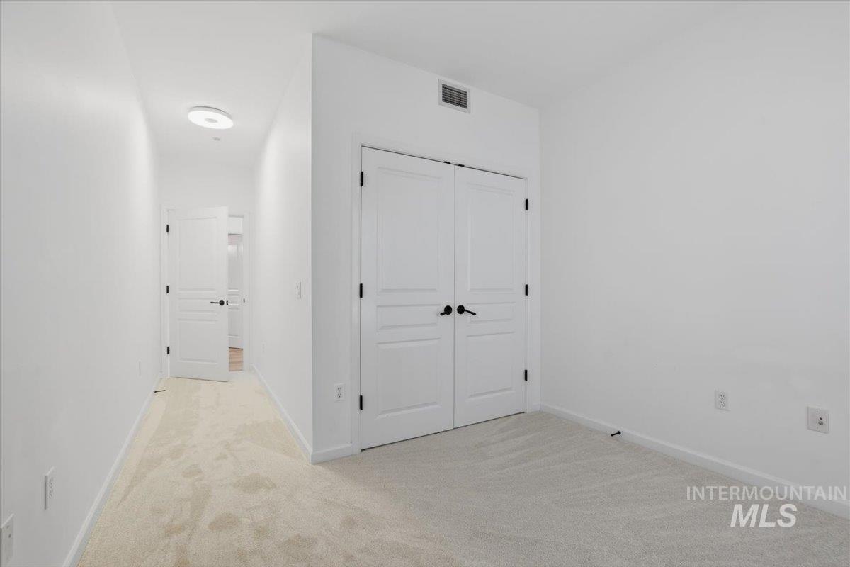 Corridor with light colored carpet and baseboards