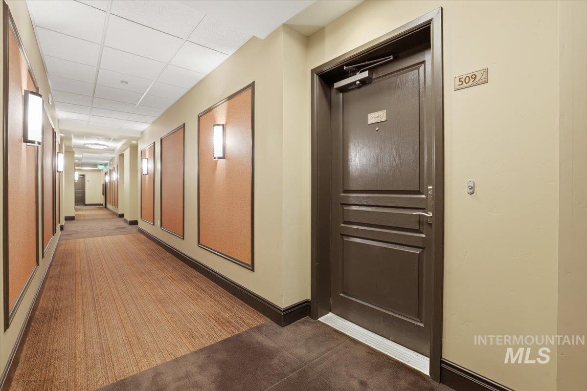 Corridor with a paneled ceiling and dark carpet