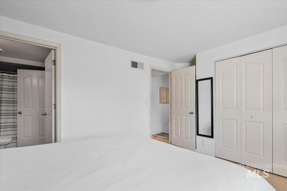 Unfurnished bedroom with a textured ceiling, ensuite bathroom, and a closet
