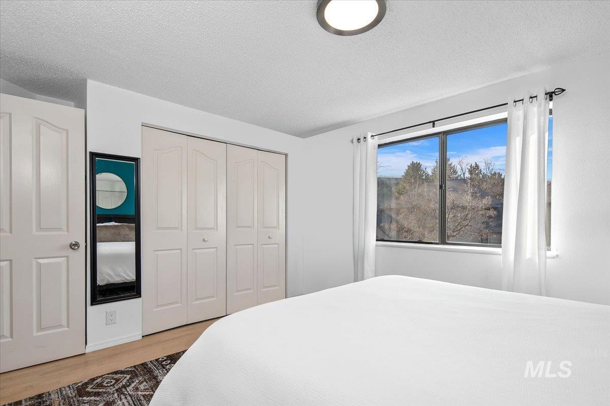 Bedroom featuring a textured ceiling, a closet, and wood finished floors