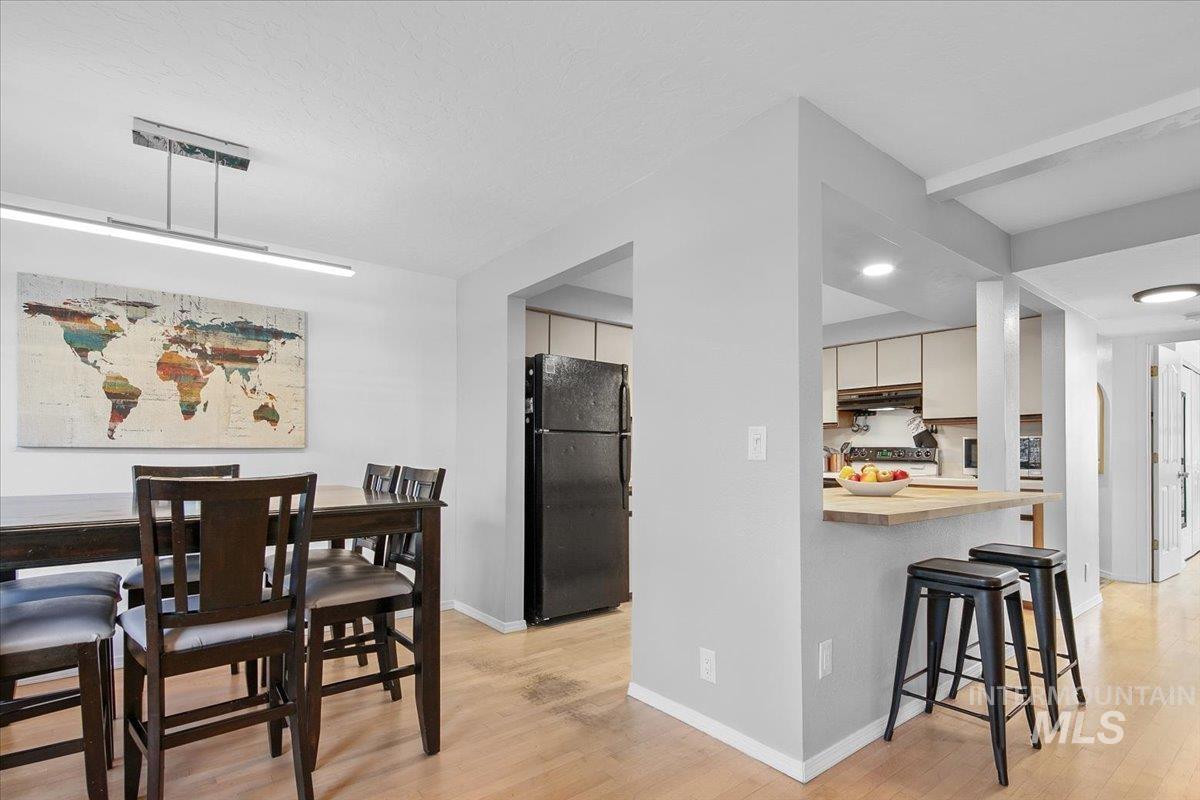 Kitchen featuring a kitchen breakfast bar, freestanding refrigerator, wood counters, light wood finished floors, and electric range