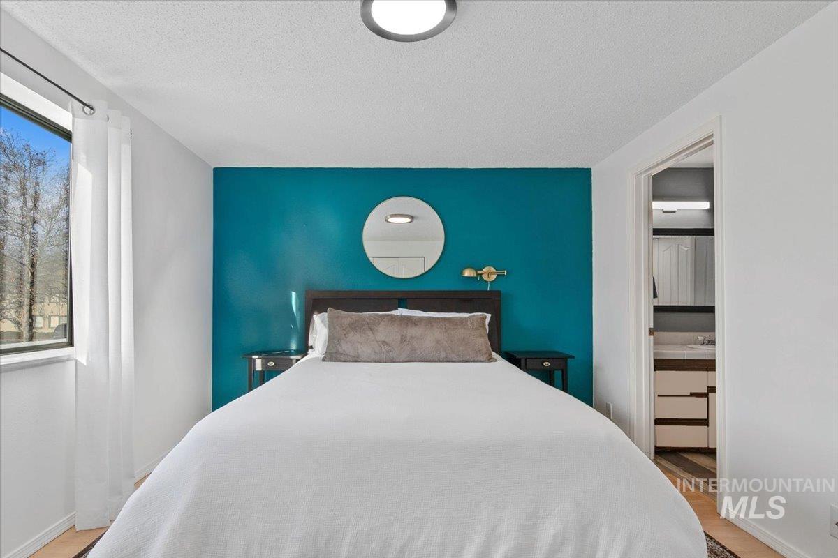 Bedroom with an accent wall, light wood-style floors, and a textured ceiling