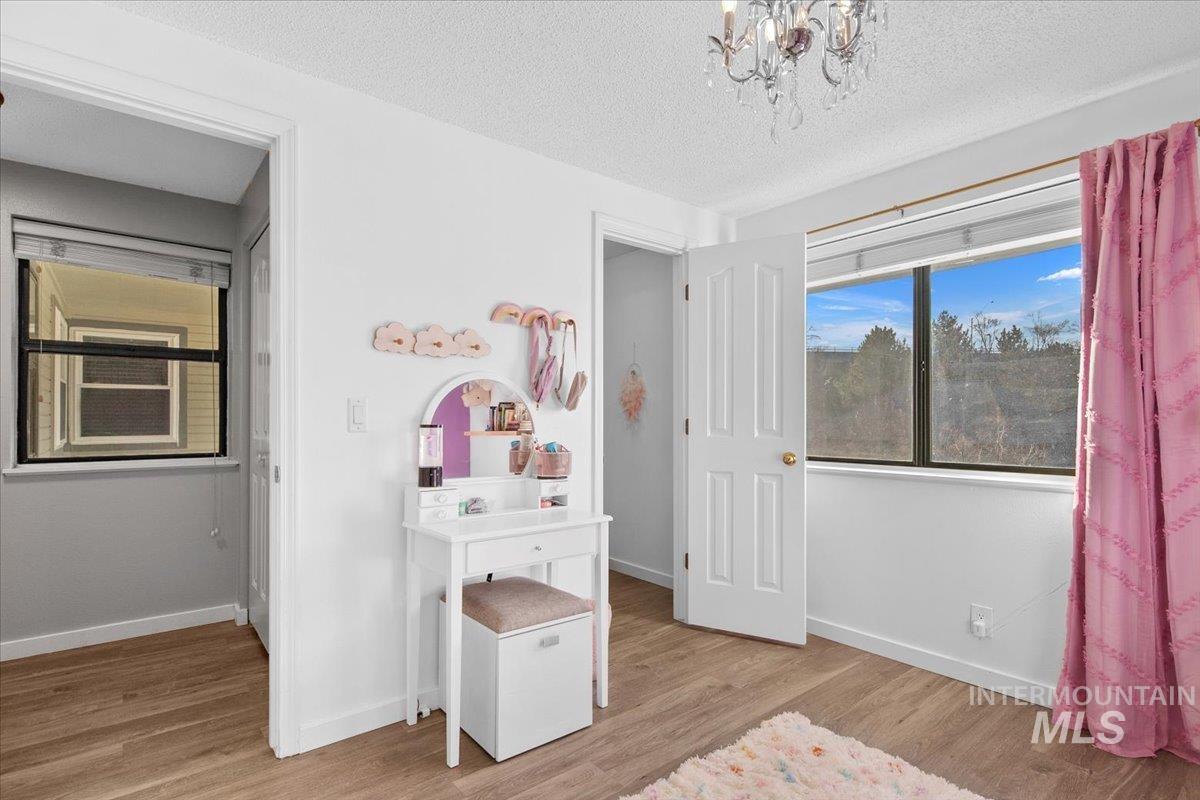 Bedroom with a textured ceiling, light wood-style floors, and a chandelier