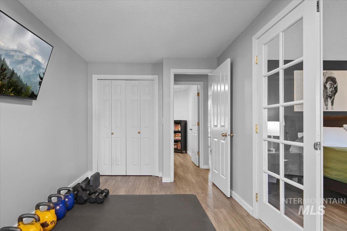 Workout area featuring a textured ceiling and light wood finished floors