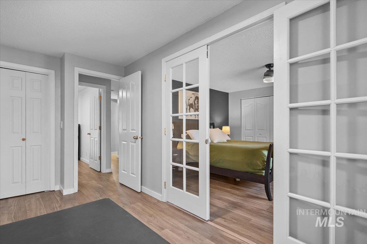 Home office with a textured ceiling, light wood-type flooring, and french doors