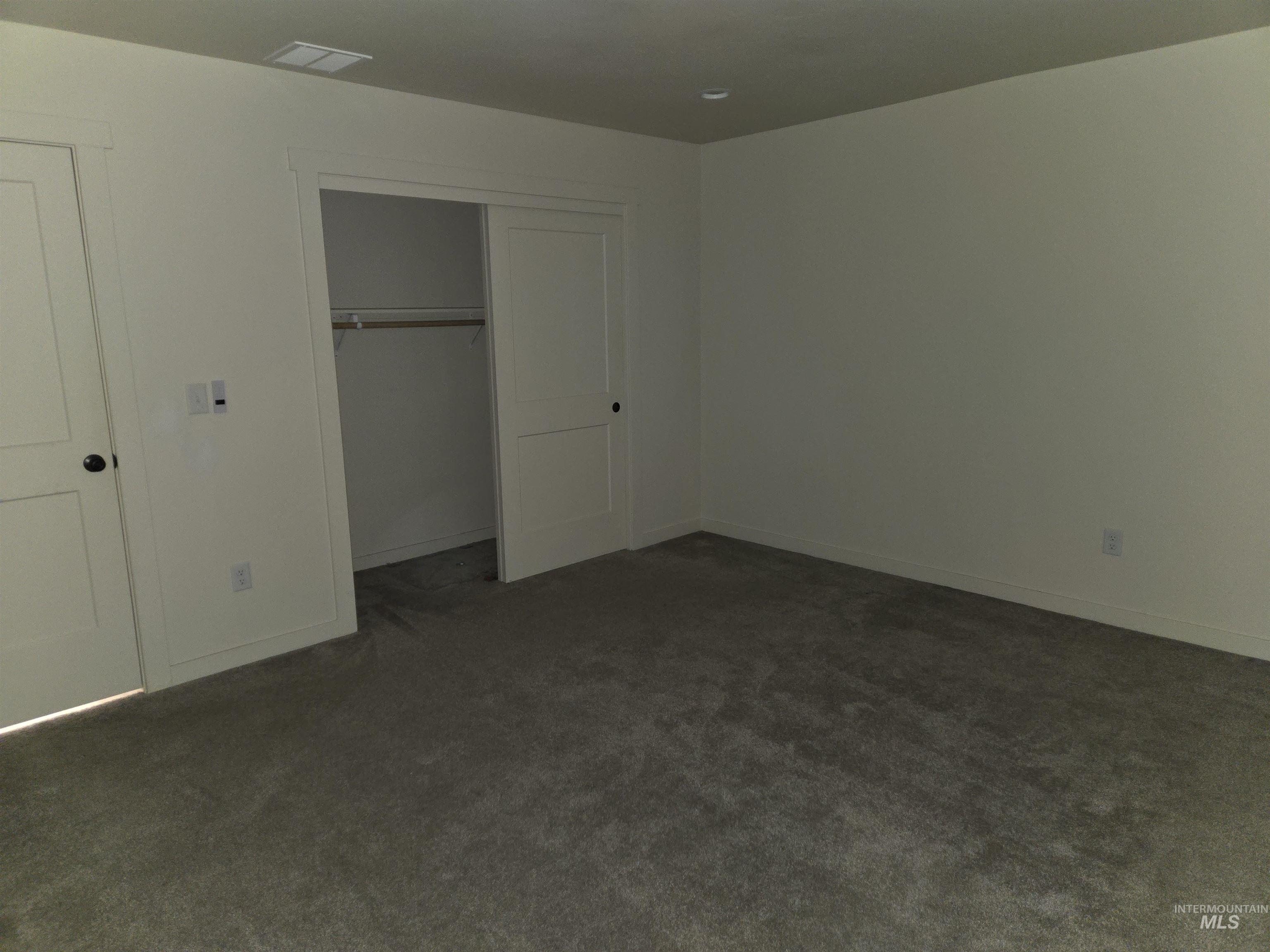 Unfurnished bedroom with dark carpet and a closet