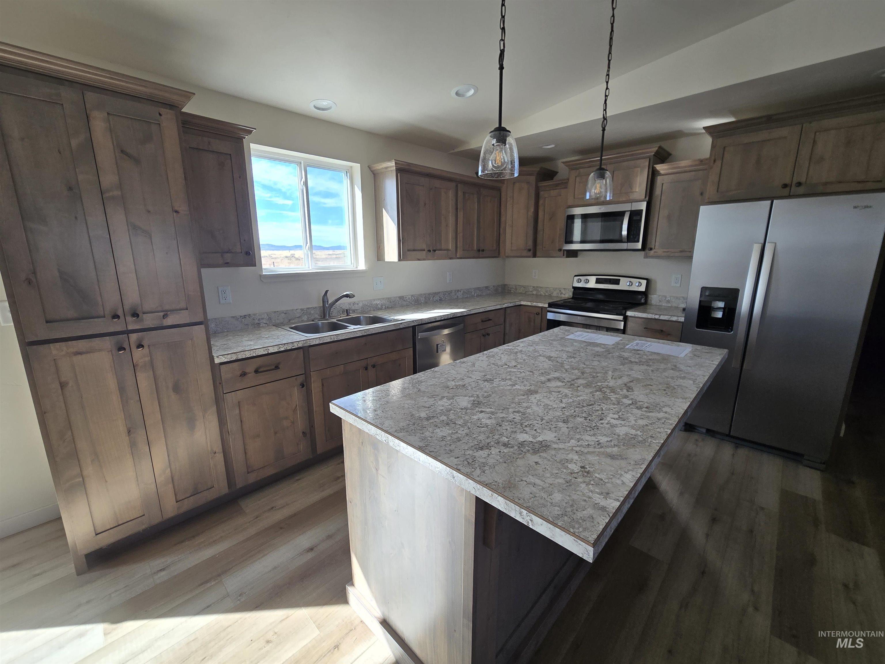 Kitchen featuring appliances with stainless steel finishes, light countertops, dark wood-type flooring, decorative light fixtures, and recessed lighting