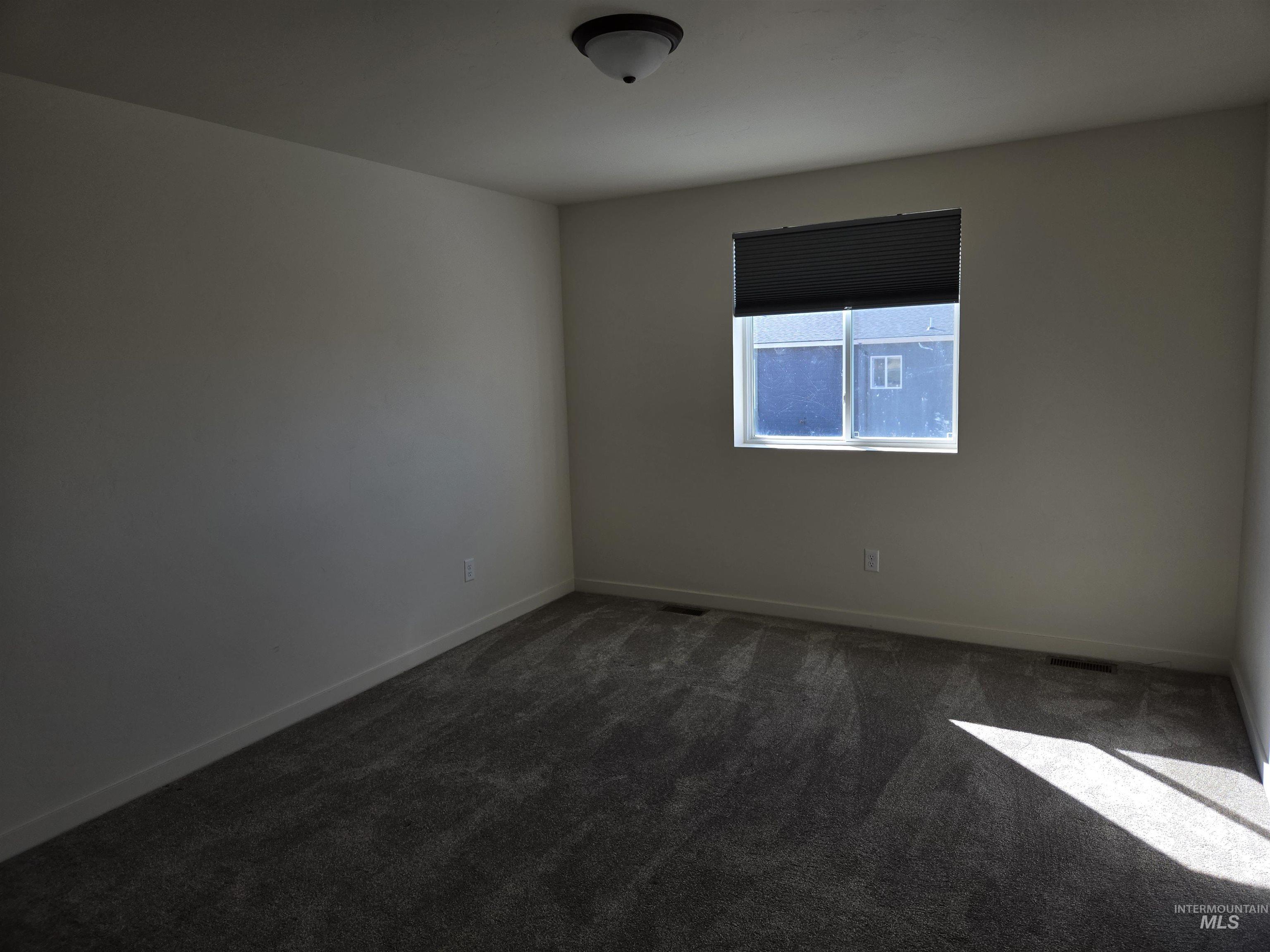 Spare room featuring dark carpet and baseboards