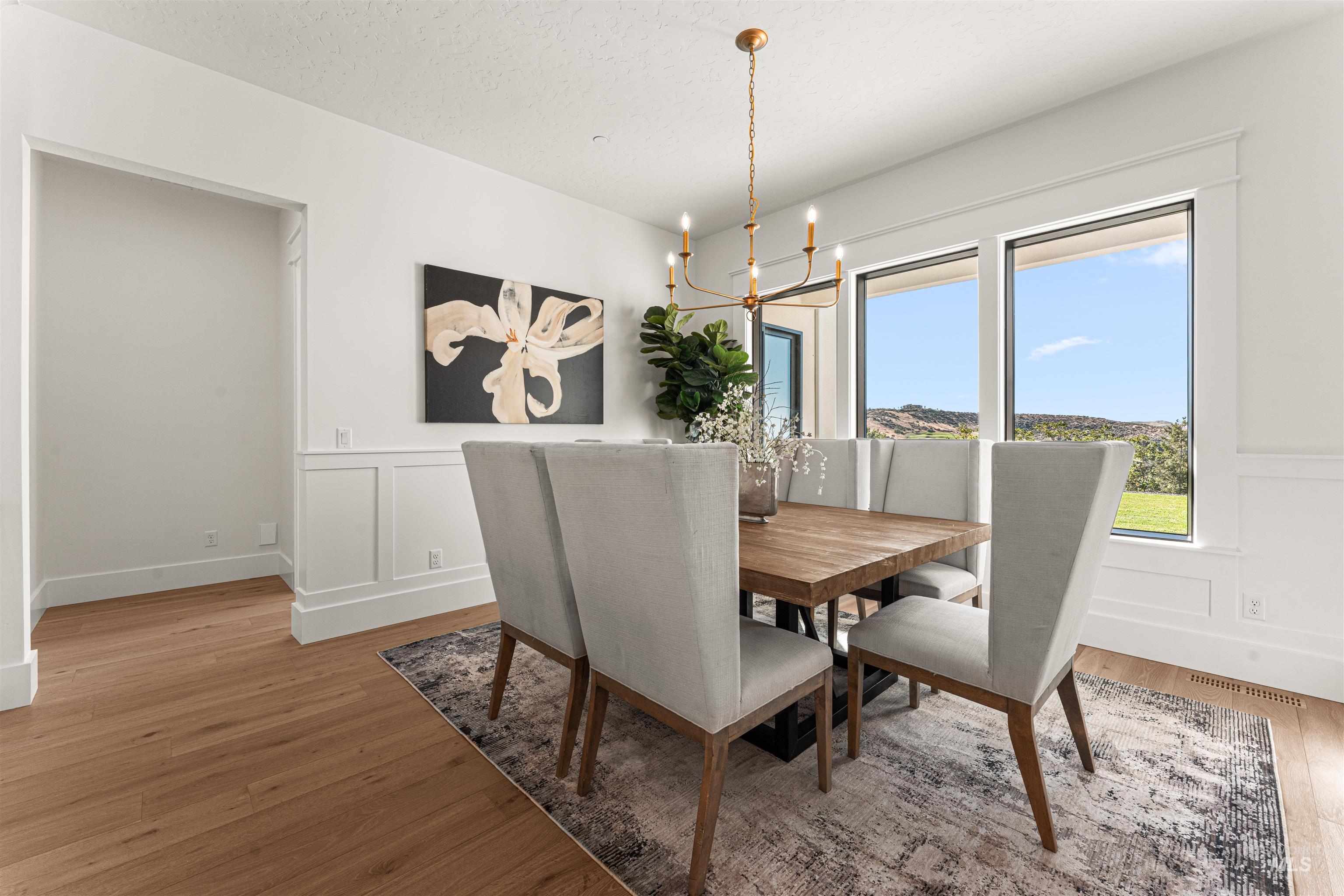 Dining room featuring a decorative wall, a wainscoted wall, a chandelier, light wood-style floors, and a textured ceiling