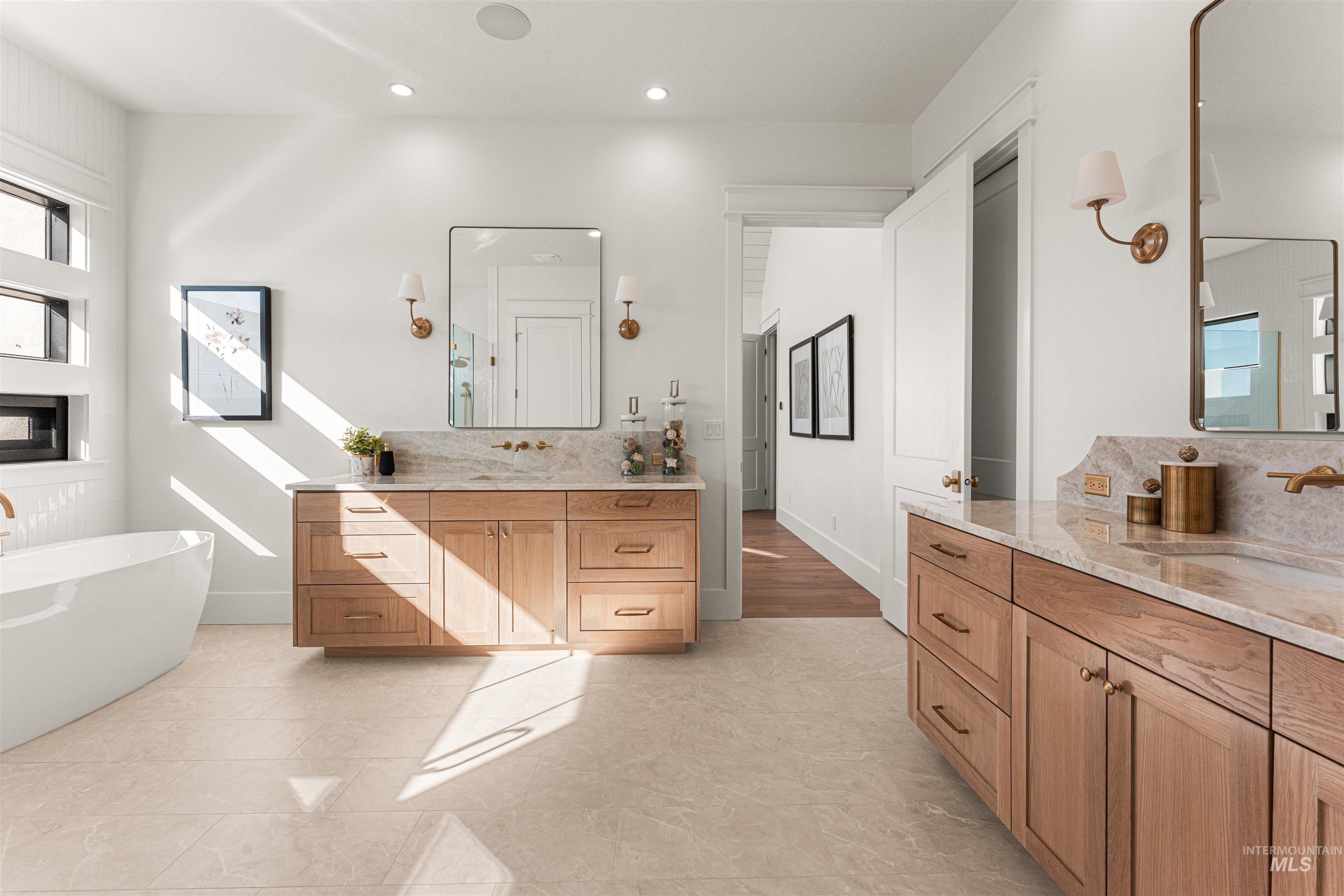 Full bathroom featuring decorative backsplash, two vanities, a soaking tub, recessed lighting, and light tile patterned flooring
