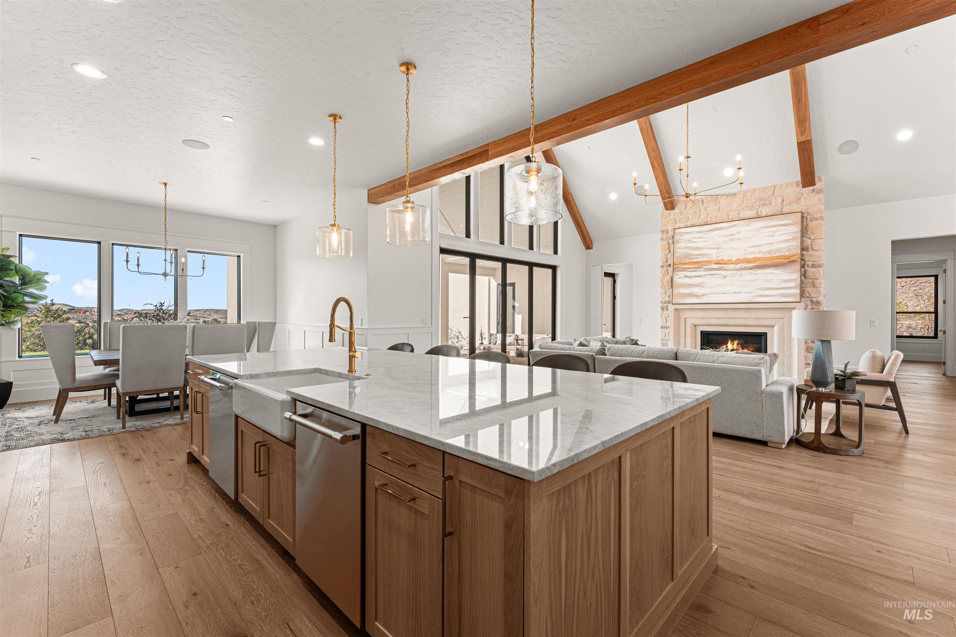 Kitchen with a chandelier, a fireplace, beam ceiling, light stone countertops, and decorative light fixtures