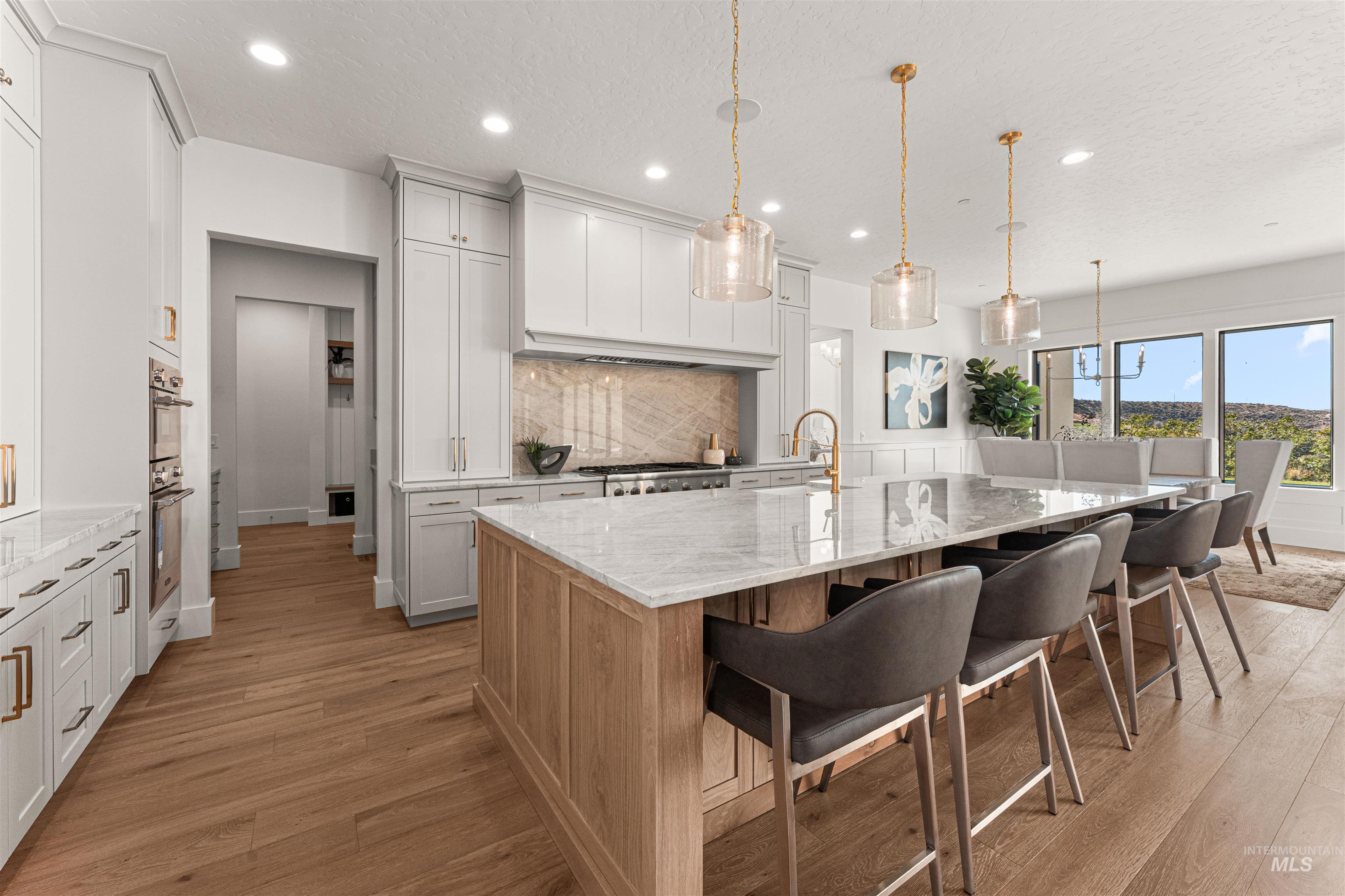 Kitchen featuring light stone countertops, a spacious island, a breakfast bar area, decorative light fixtures, and light wood-style floors