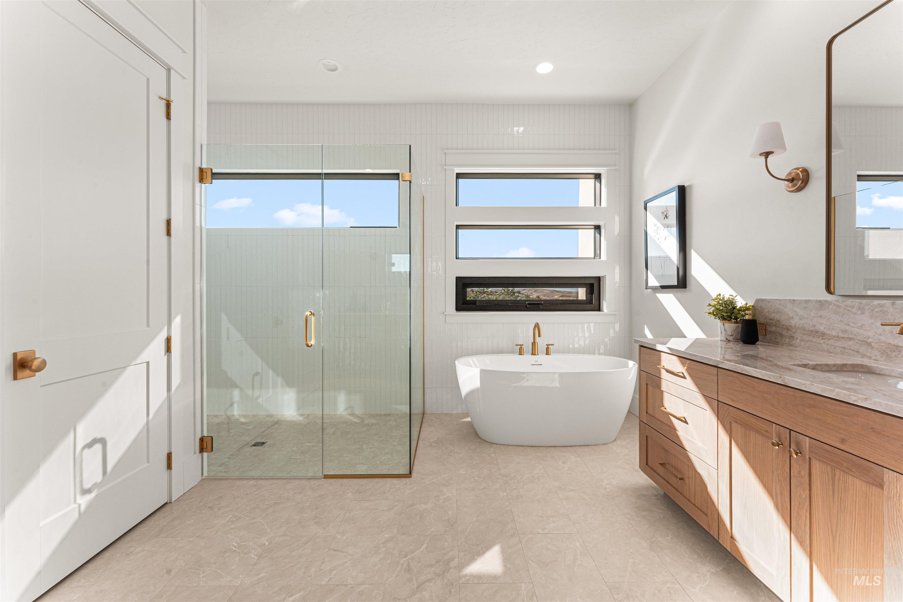 Bathroom featuring vanity, a soaking tub, a stall shower, healthy amount of natural light, and recessed lighting
