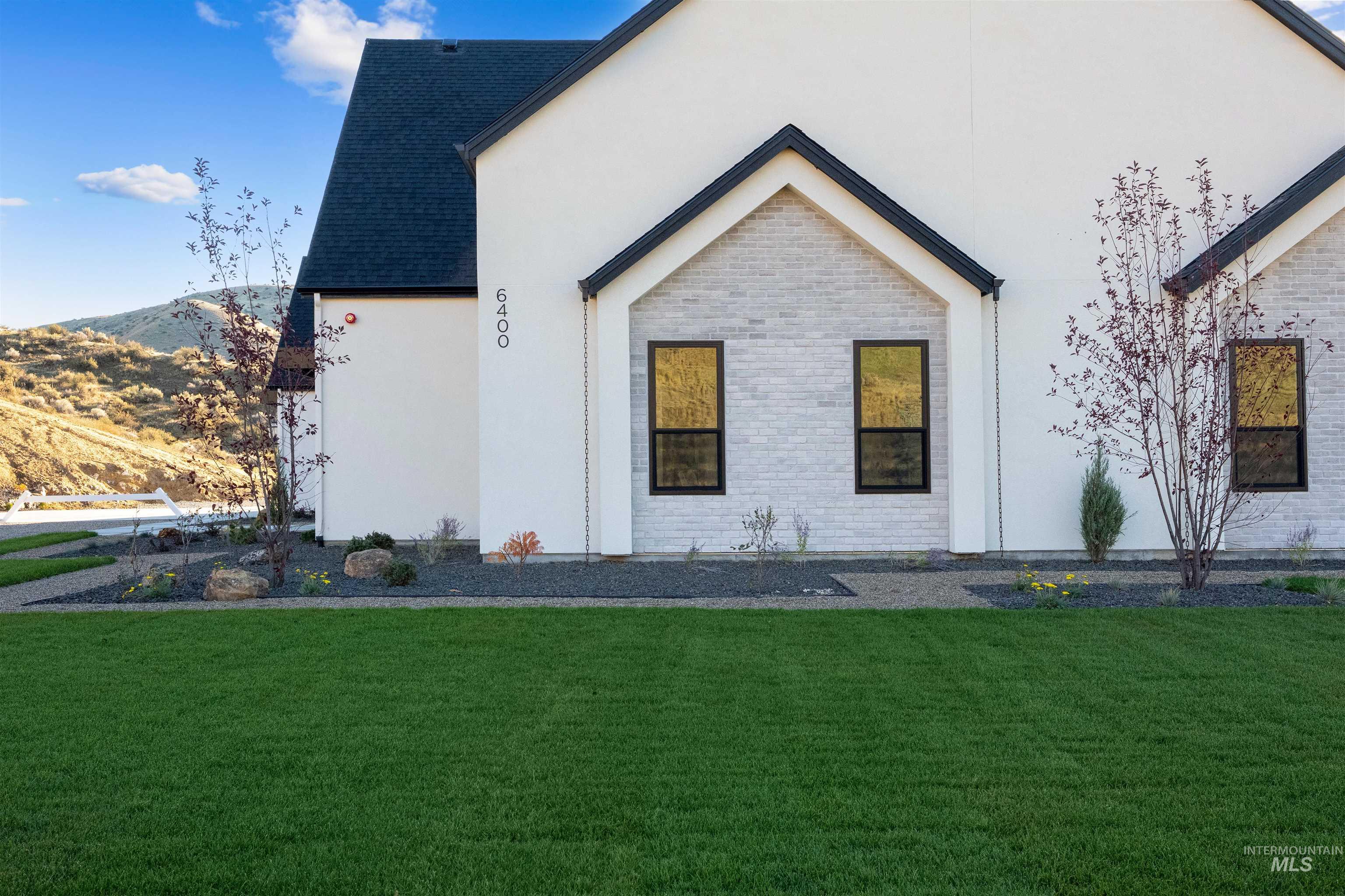 View of front of property with a front yard, stucco siding, brick siding, and roof with shingles