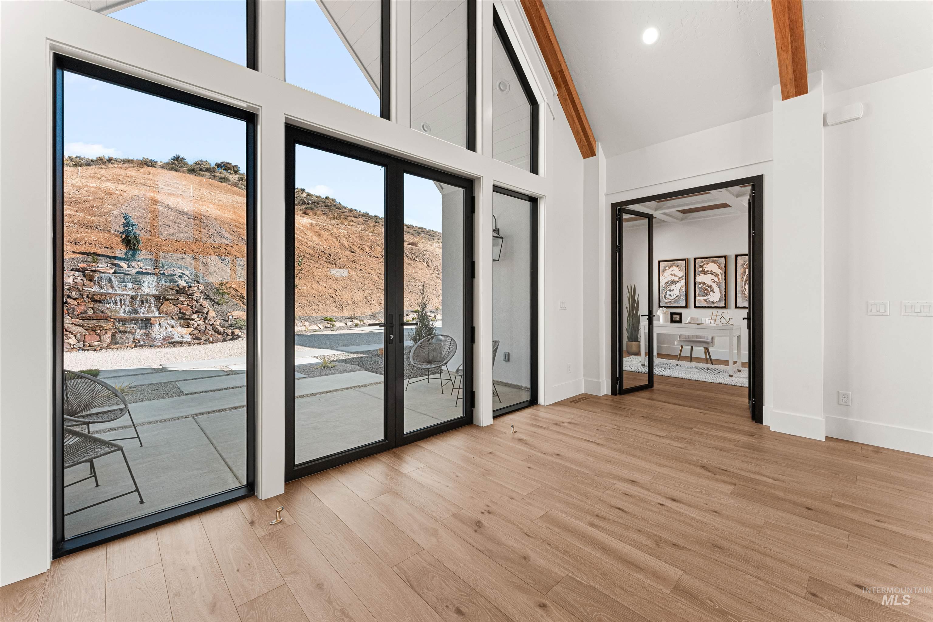 Doorway to outside with wood finished floors, high vaulted ceiling, and beam ceiling
