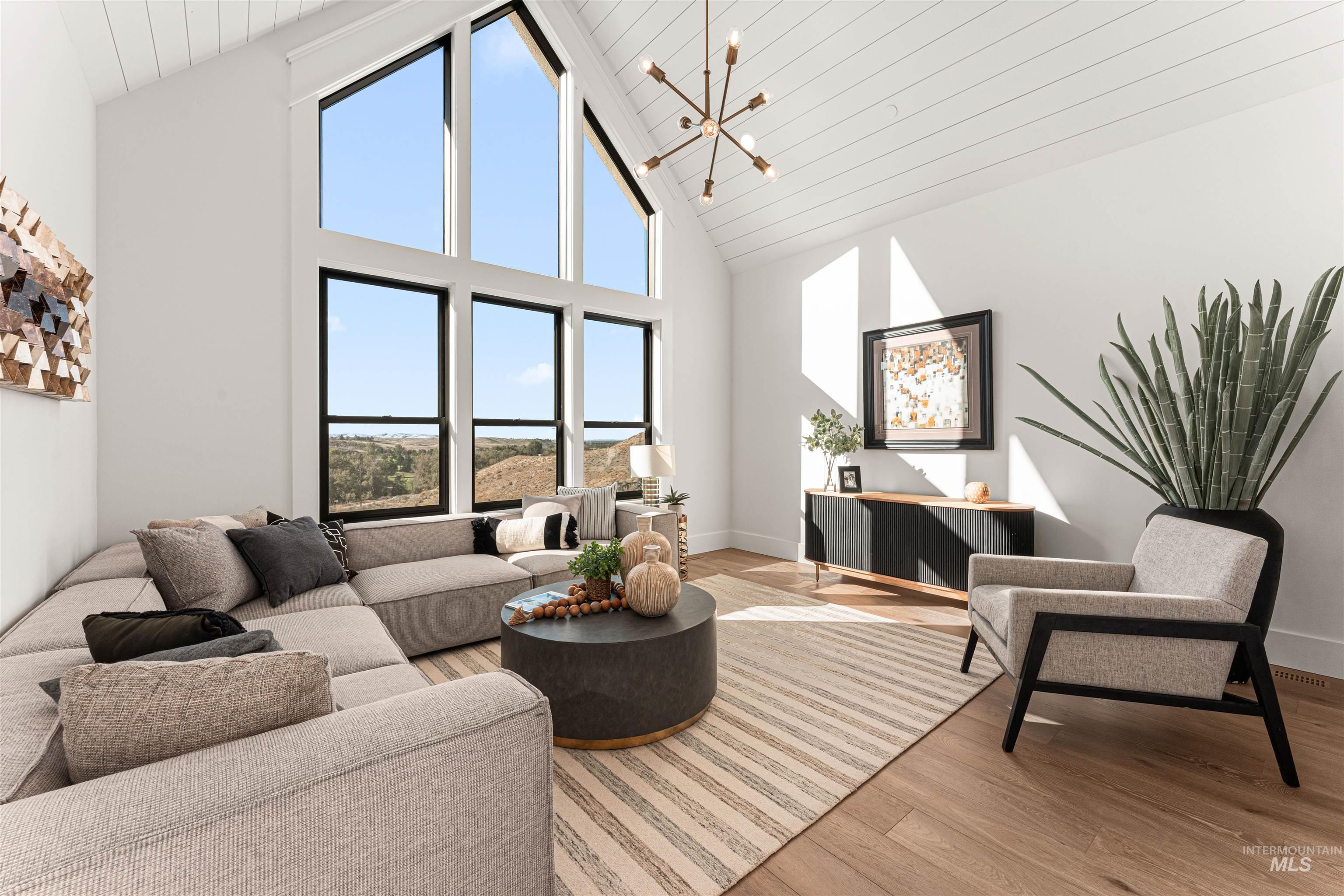 Living room featuring high vaulted ceiling, light wood-style floors, a chandelier, and wooden ceiling