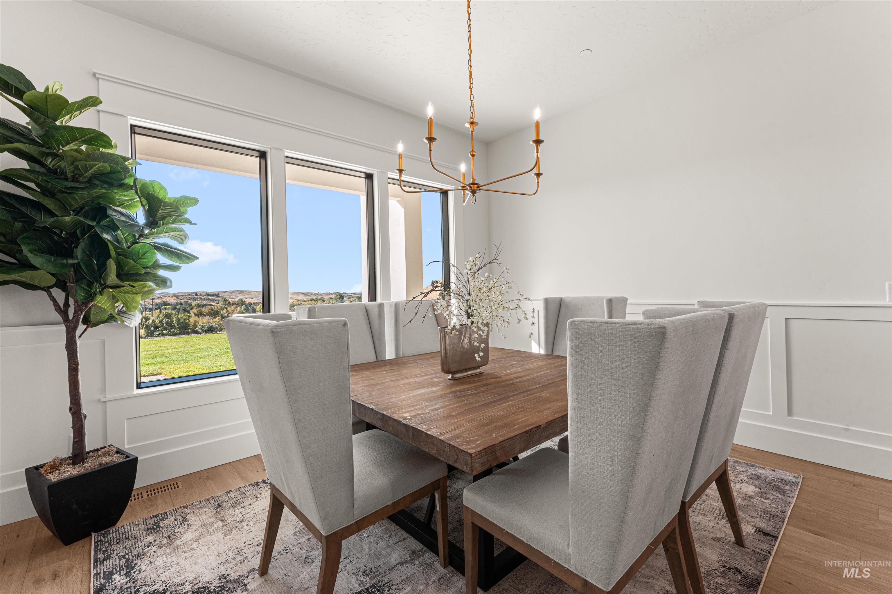 Dining space featuring a decorative wall, light wood-style floors, a wainscoted wall, and a chandelier