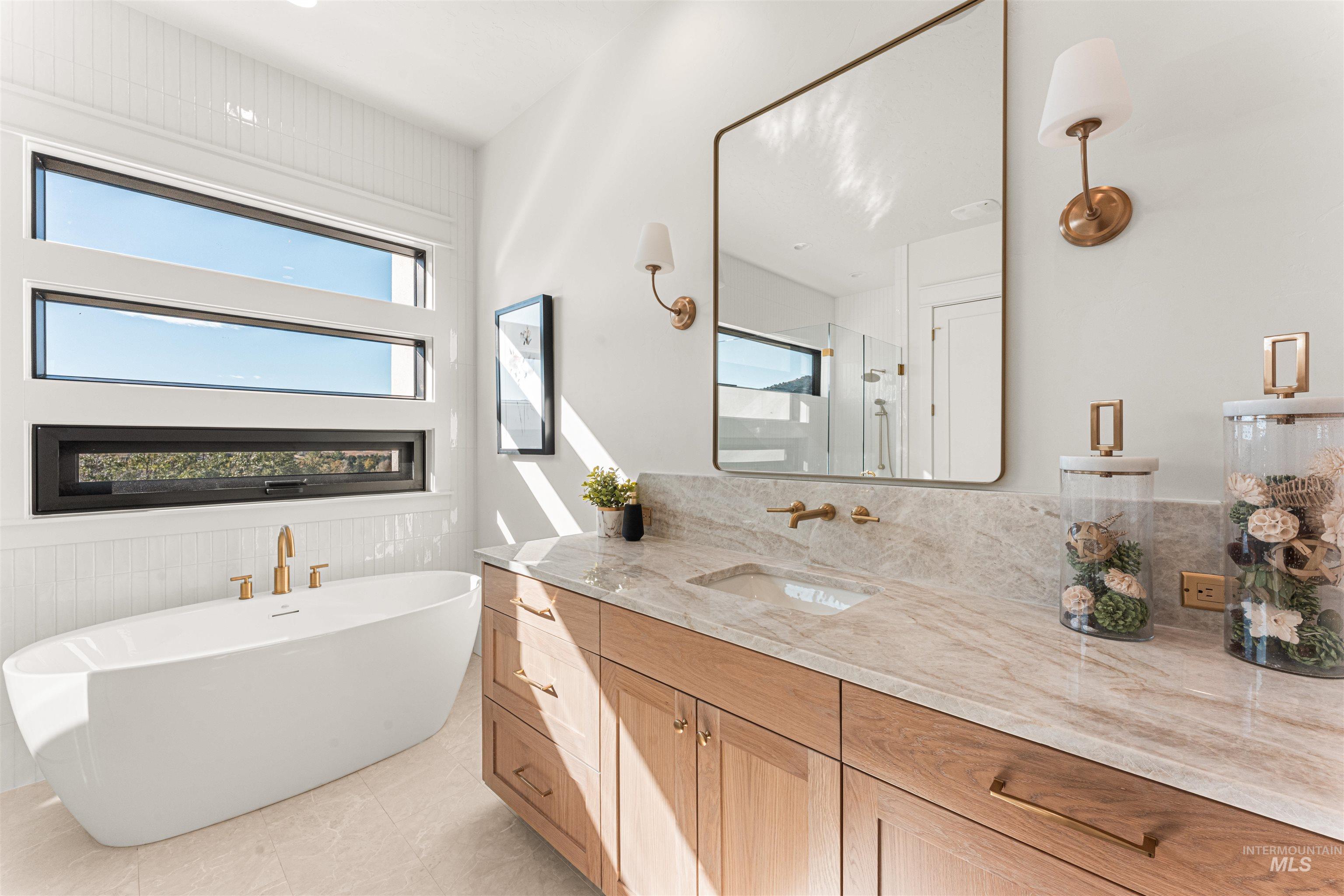 Bathroom featuring vanity, a stall shower, a freestanding bath, and light tile patterned floors