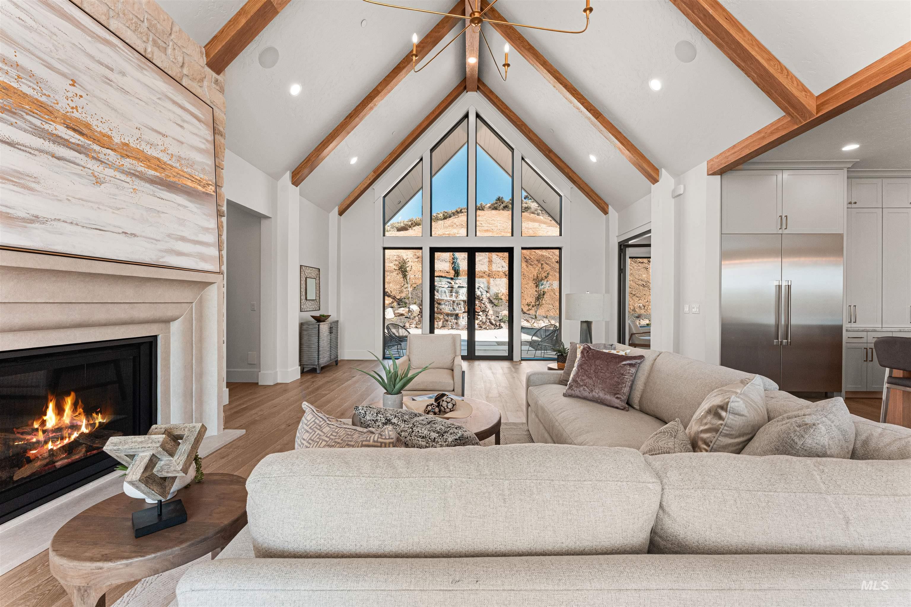 Living room featuring beam ceiling, high vaulted ceiling, wood finished floors, a glass covered fireplace, and recessed lighting