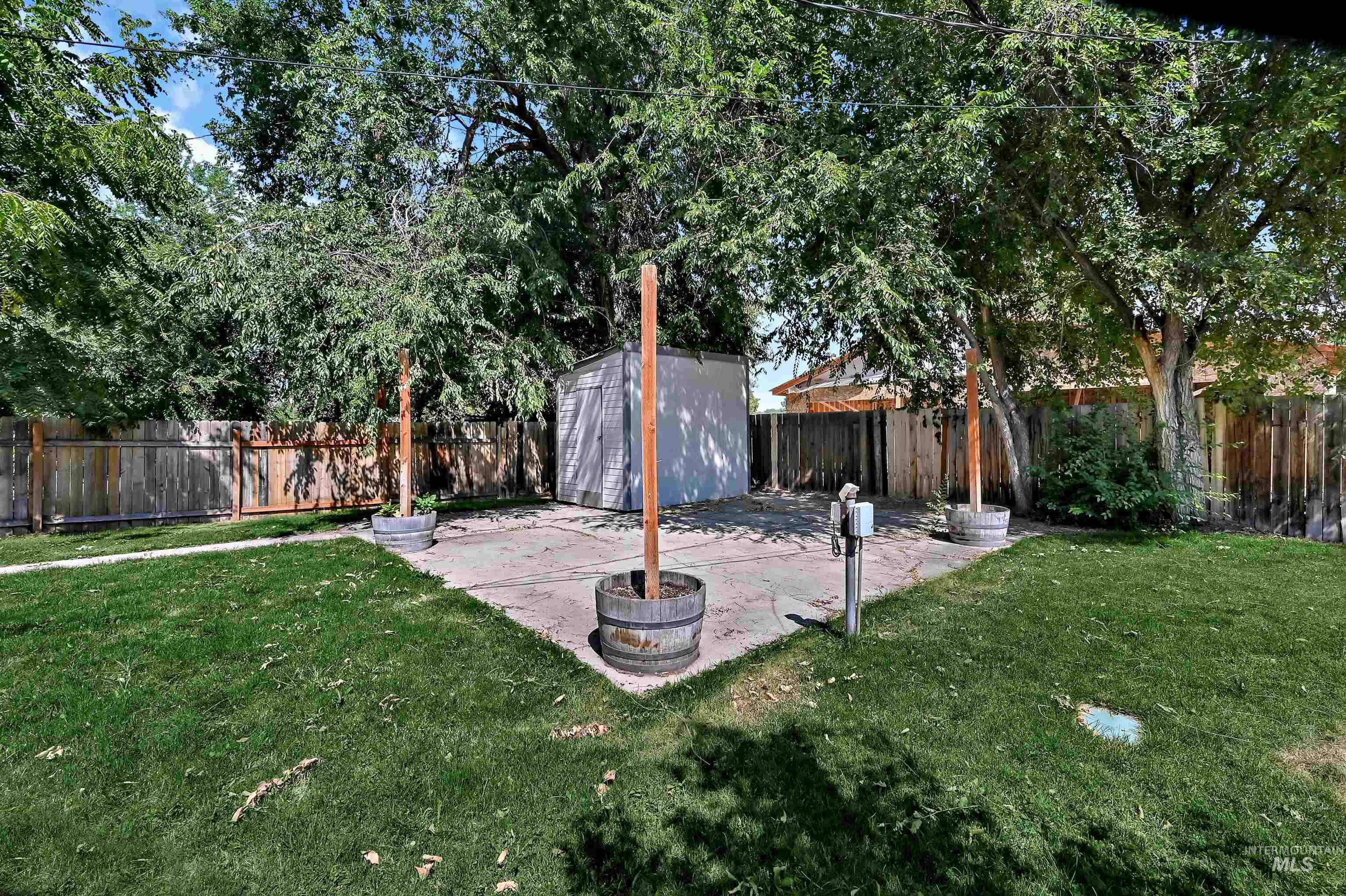 Fenced backyard featuring a storage shed and a patio
